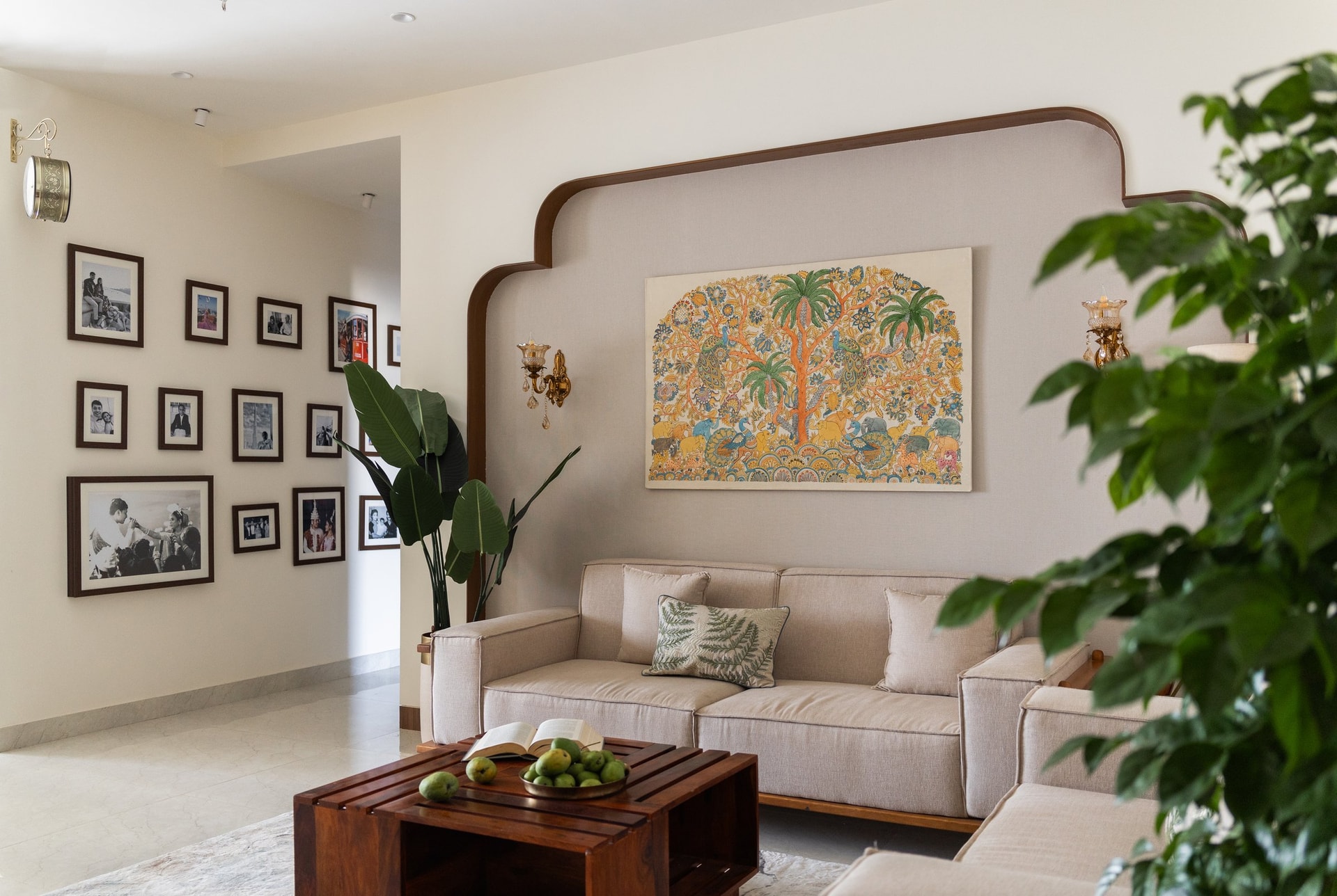 The arched alcove behind the seating, framing a single piece of folk art alongside a wall of family photographs