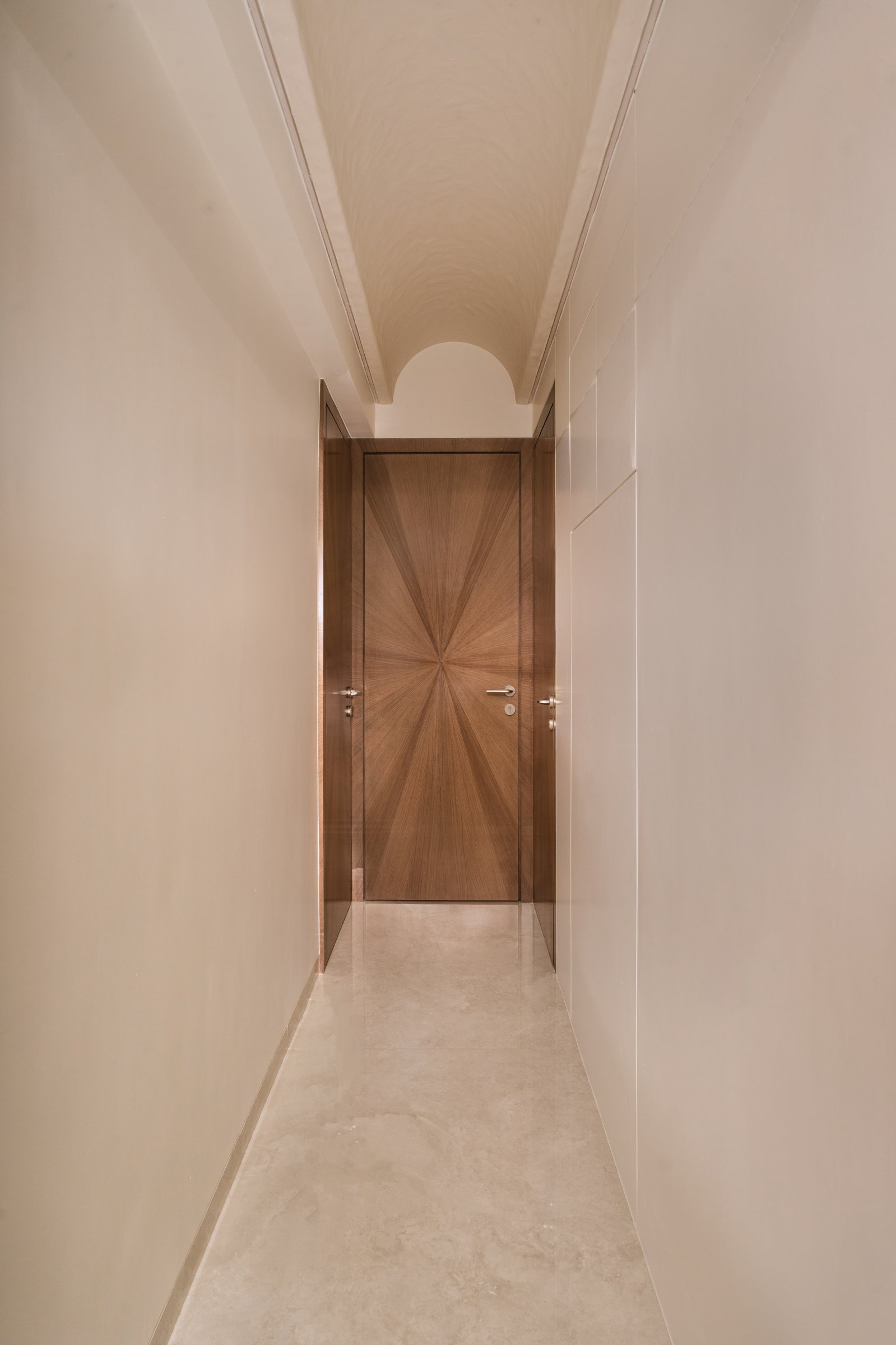 A sunburst-veneer door closes the corridor with a quiet moment of geometry