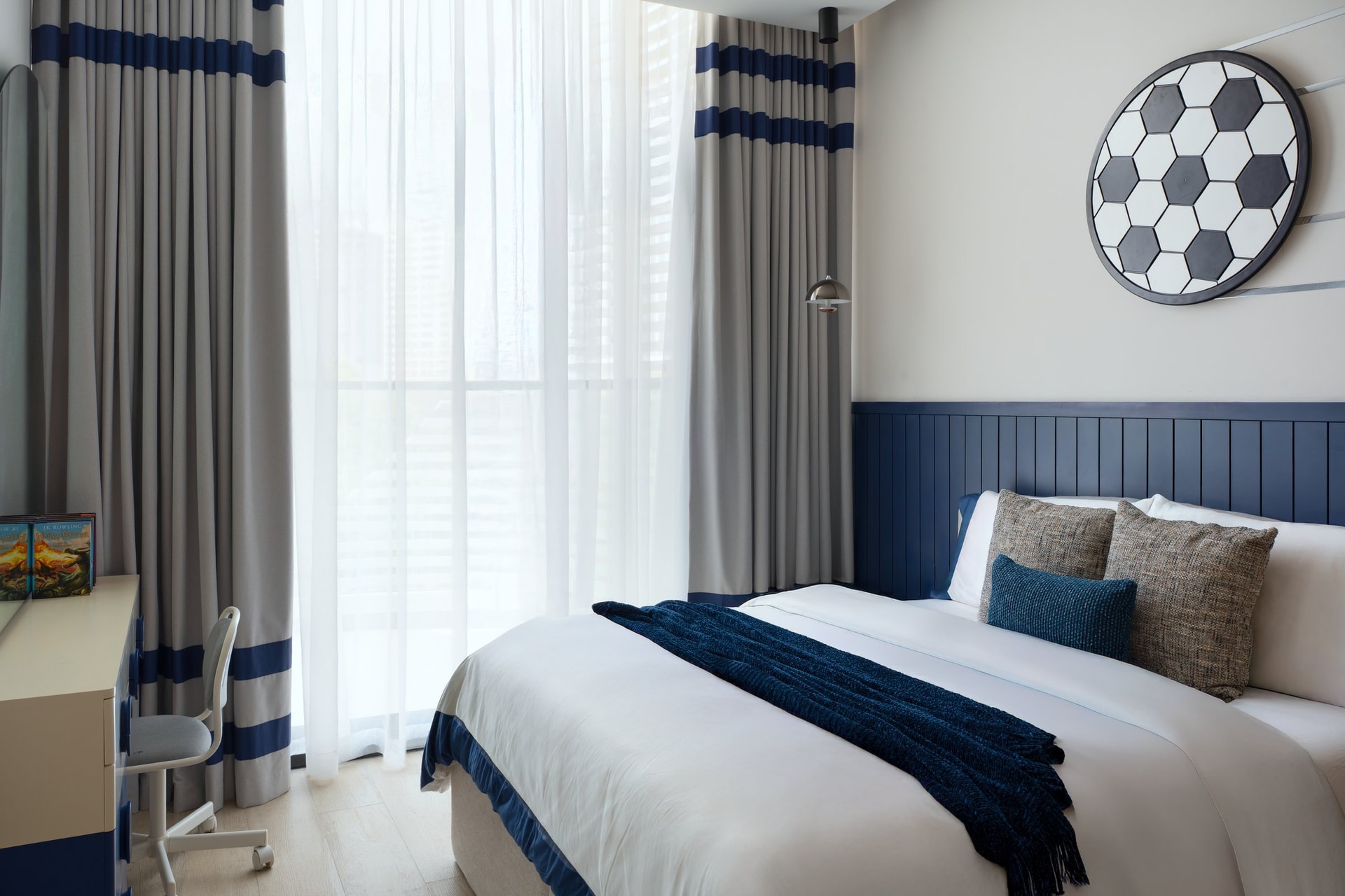 The children's room, where a navy wainscot and a circular soccer-ball mirror signal the occupant without overplaying it