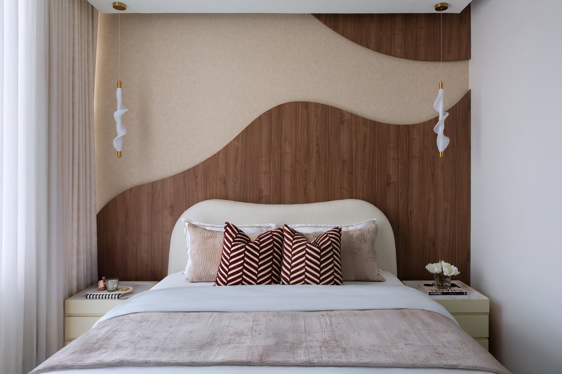 Seen head-on, the wall reads almost like a relief sculpture, with ribbon-form pendants flanking the bed in place of conventional sconces