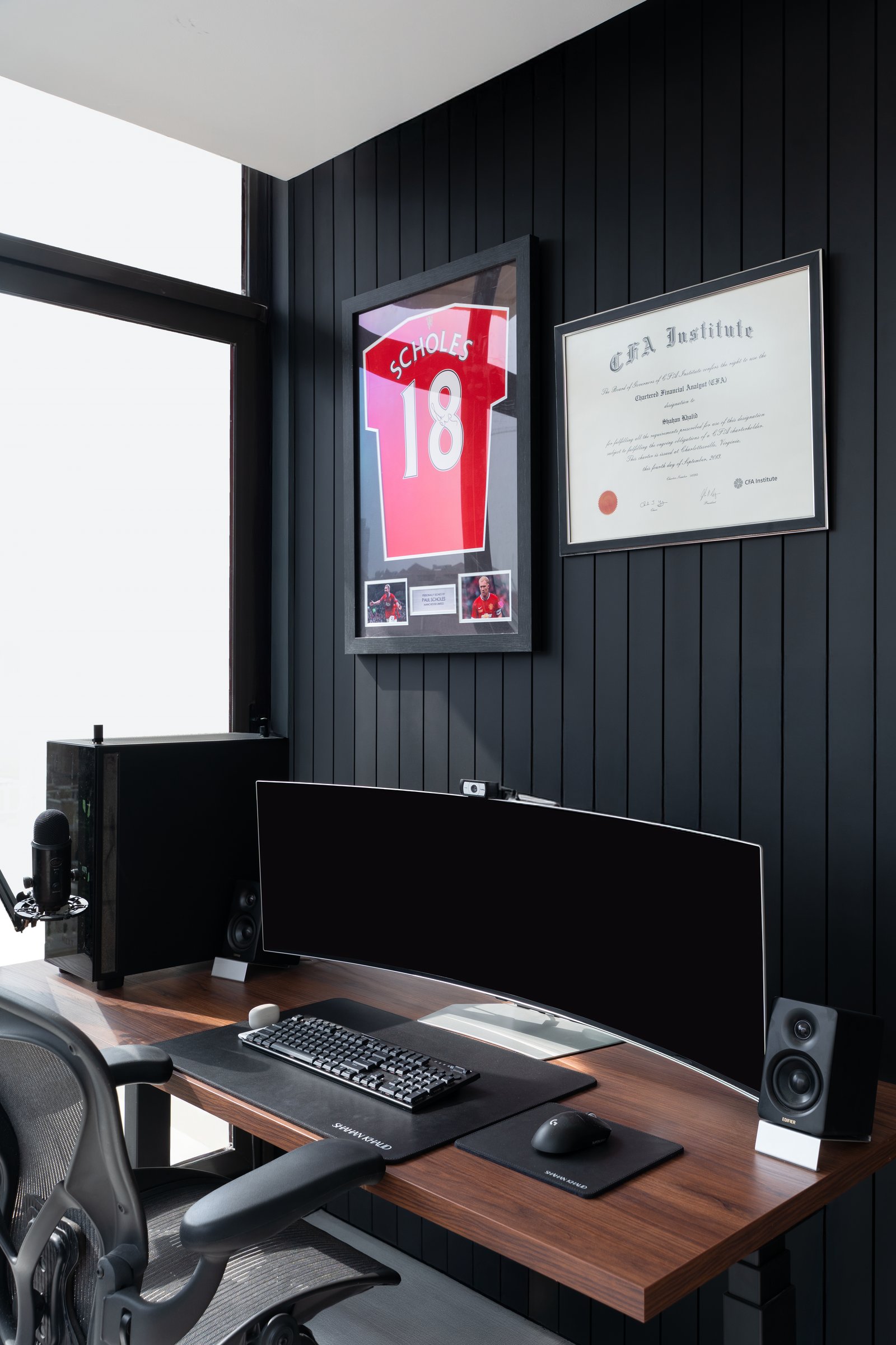 The desk wall in dark vertical panelling, grounded by personal markers rather than generic study iconography