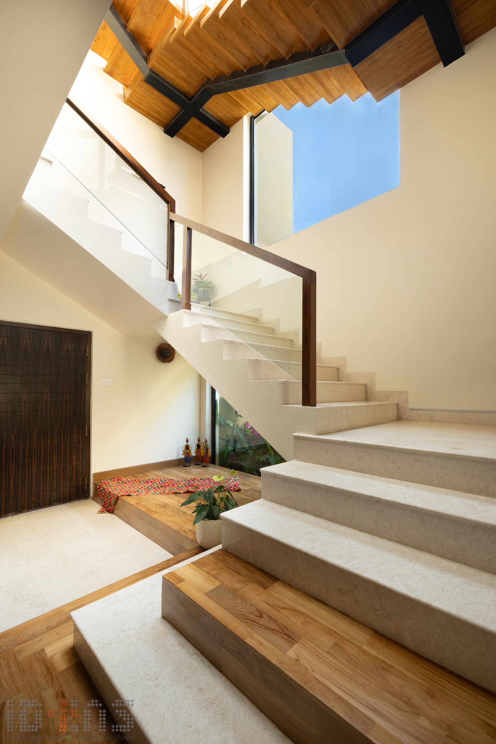 The internal staircase opens beneath a pitched wood ceiling and a square skylight, with a folk-art tableau at the base of the climb
