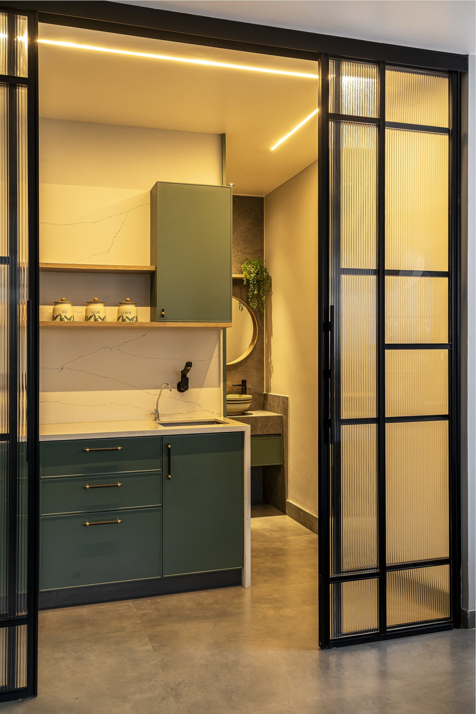 Inside the pantry: sage green cabinetry, veined stone backsplash, and a cove-lit ceiling carry the project's finish into the smallest room