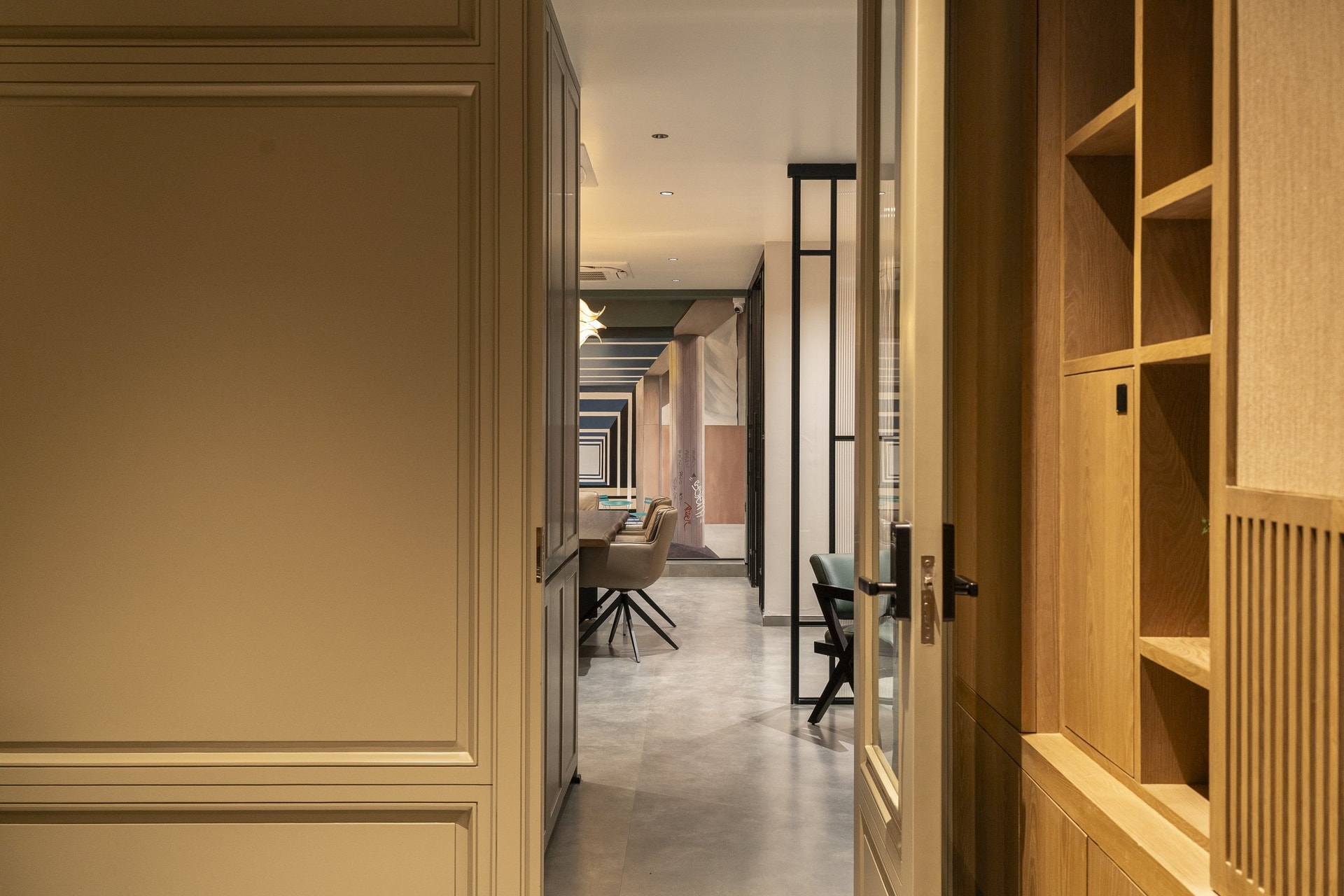 The corridor between foyer and main volume, framed by panelled cabinetry on one side and slatted wood on the other