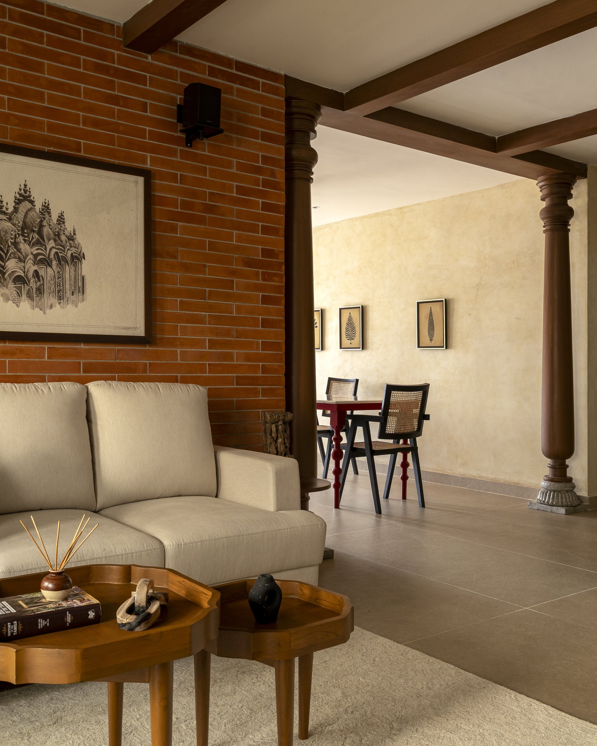 Solid wood columns with carved stone bases mark the threshold from living to dining, a gesture lifted directly from the traditional Tamil home