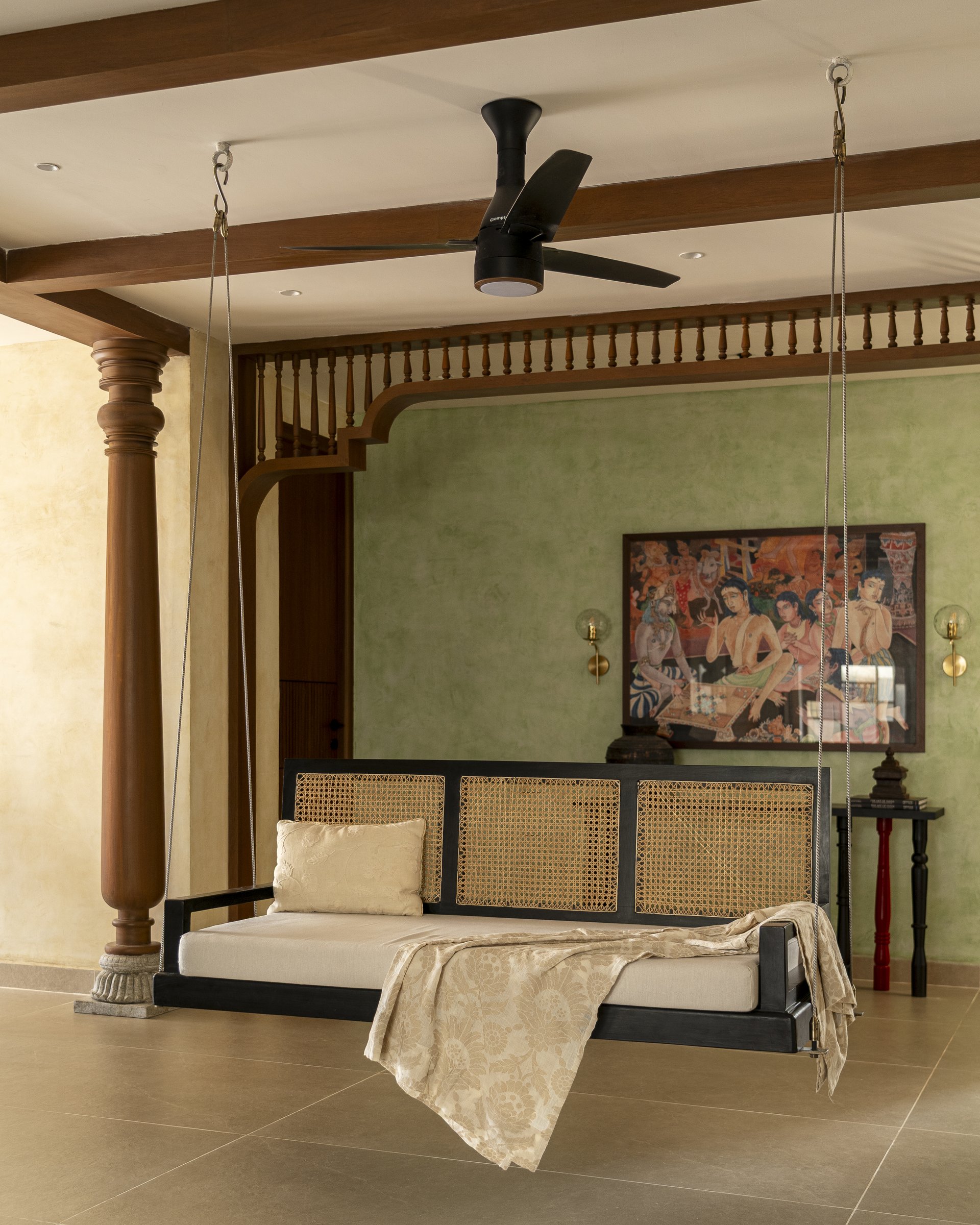 The second swing, hung against a moss-green plaster wall with a Tanjore-inspired painting above, the oonjal reset as a working piece of furniture