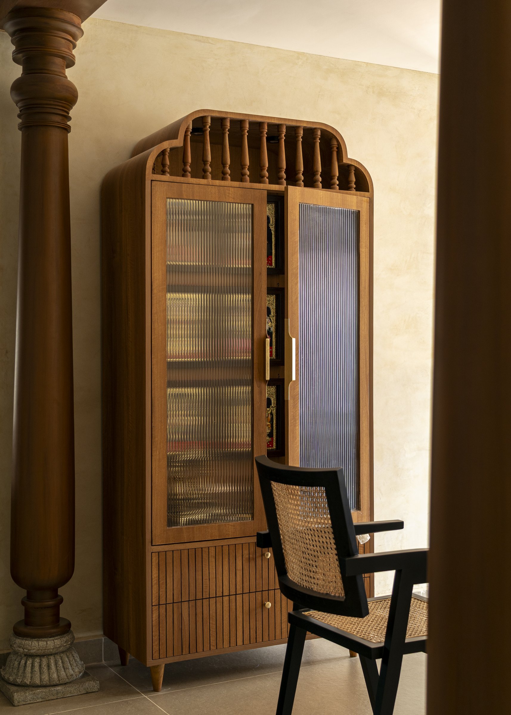 The bespoke pooja cabinet in teak, its arched profile and turned baluster crown reworking the traditional almirah for apartment proportions