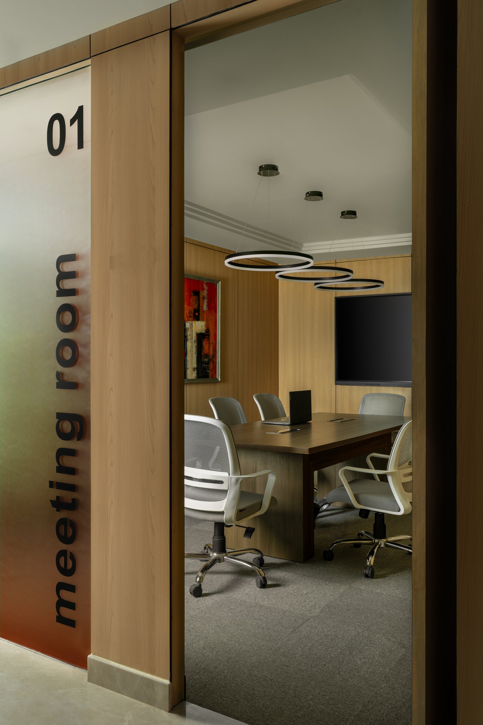 The general meeting rooms, marked by minimal etched-glass signage and a trio of ring pendants