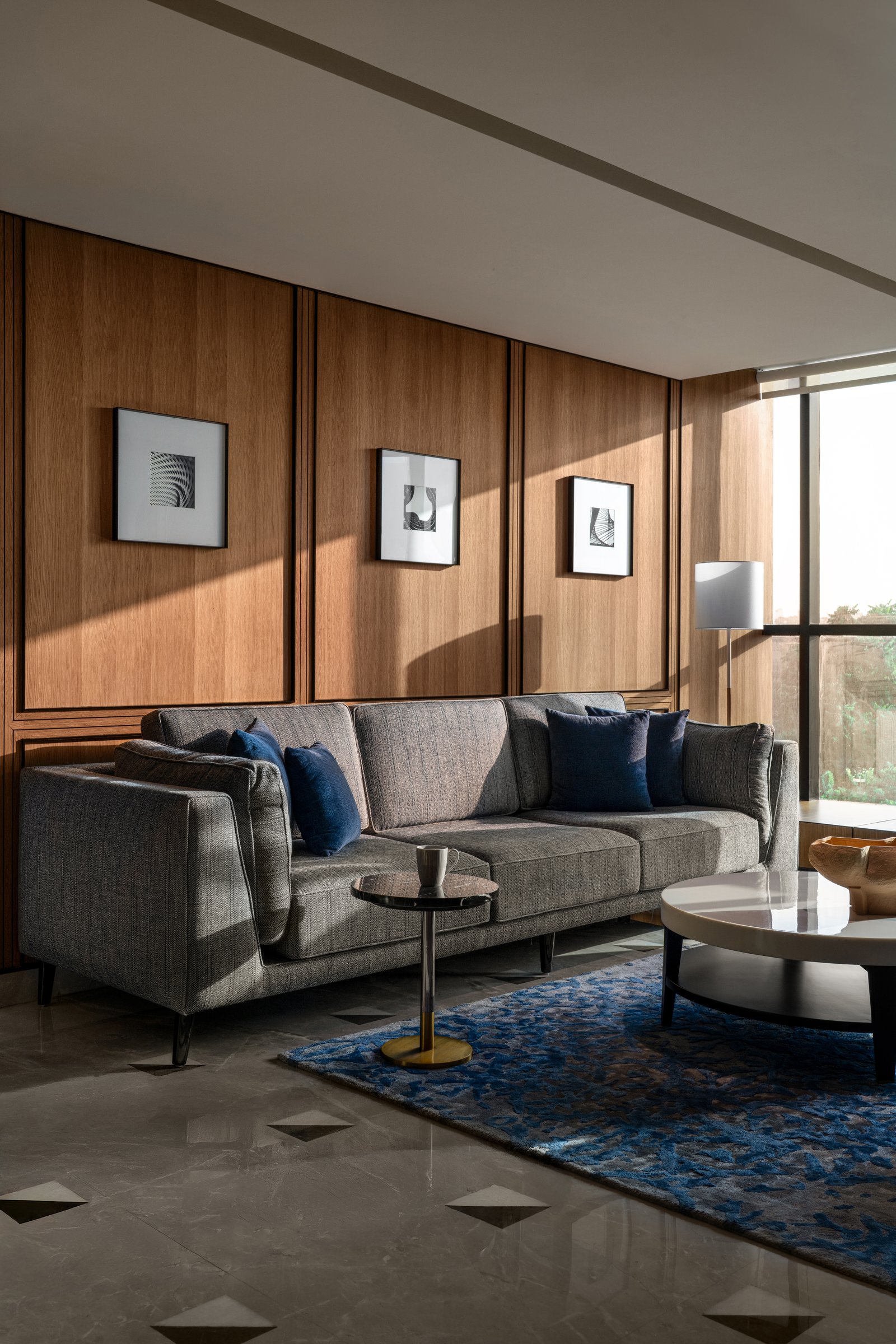Late-afternoon light animates the wood panelling above the lounge's grey sofa