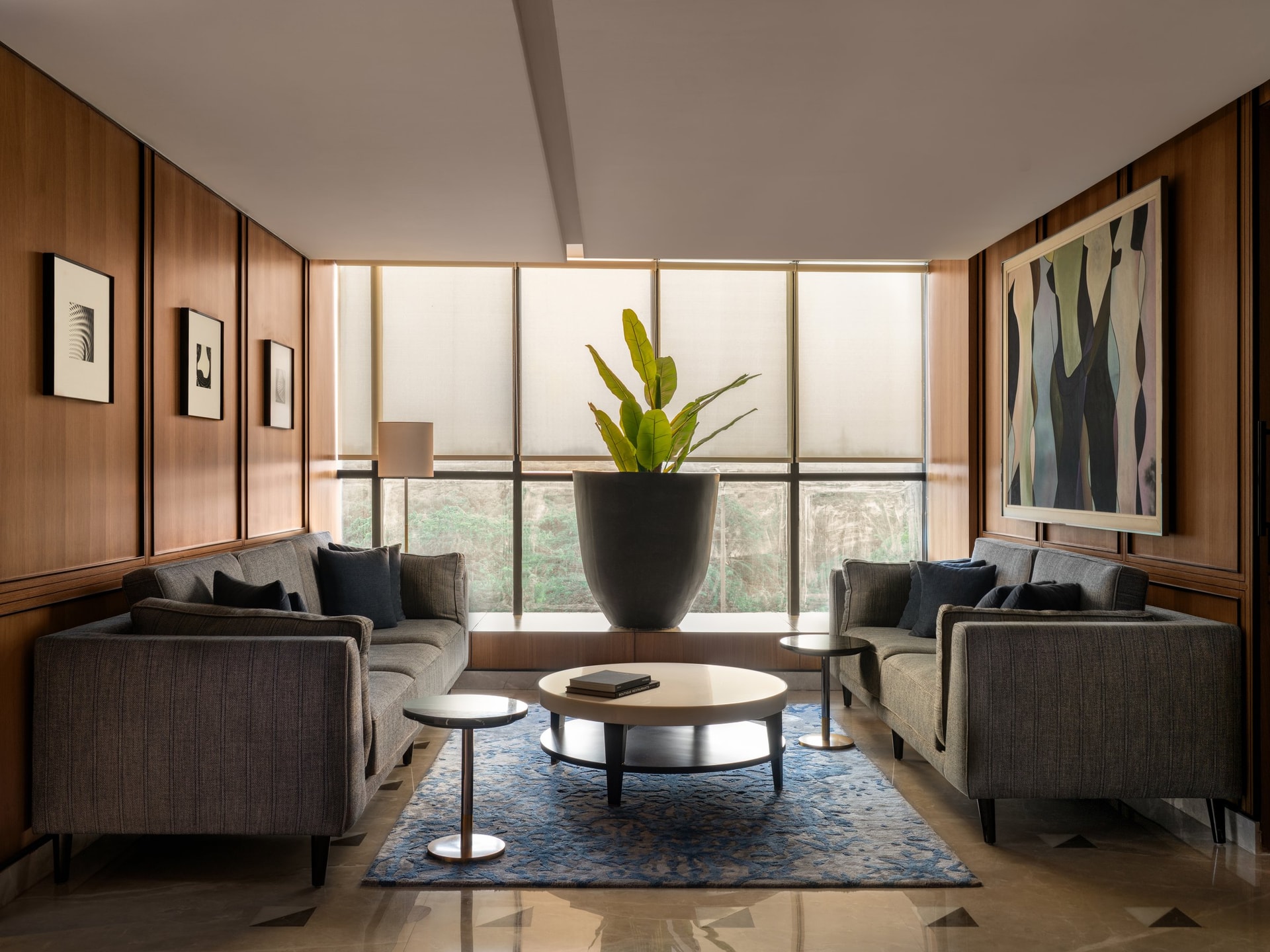 The primary lounge, where wood panelling and a single banana-leaf gesture set the project's tone of composed restraint