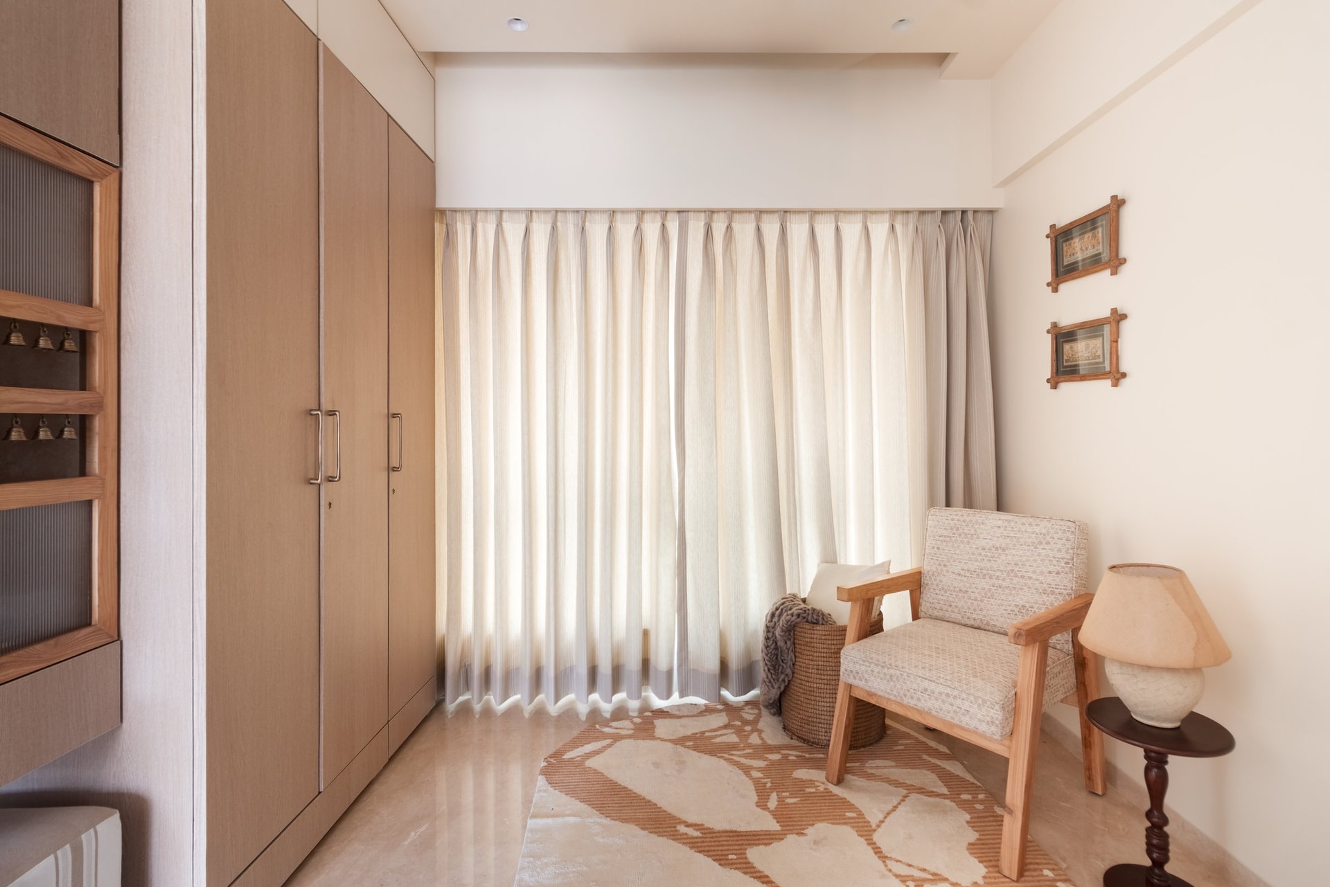 A wider view of the den, where tall oak wardrobes, sheer curtains, and a reeded-glass ritual cabinet allow a single room to hold many functions