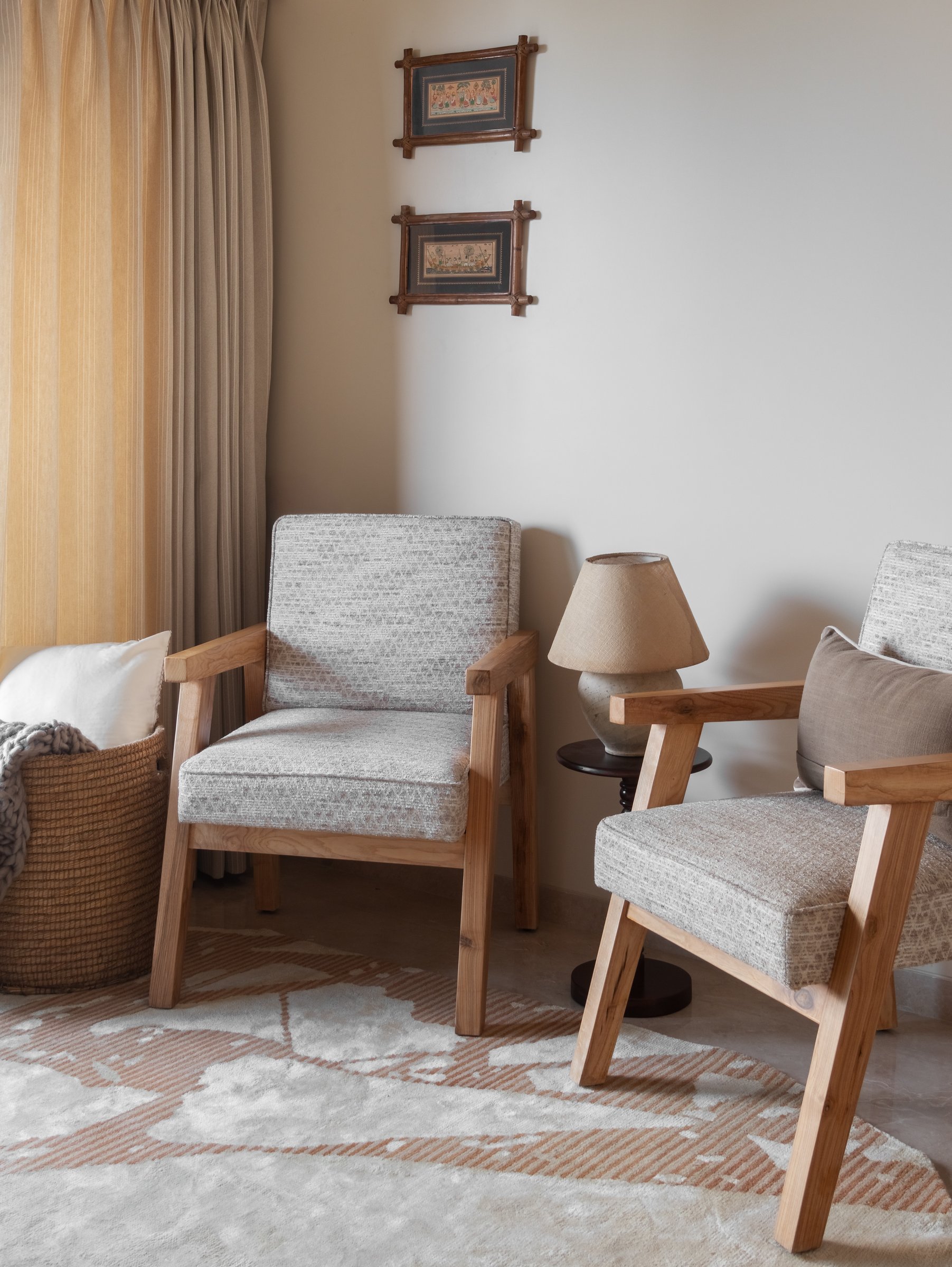 The den, where teak-framed armchairs and small framed works recall the lineage of Indian institutional furniture without quoting it directly