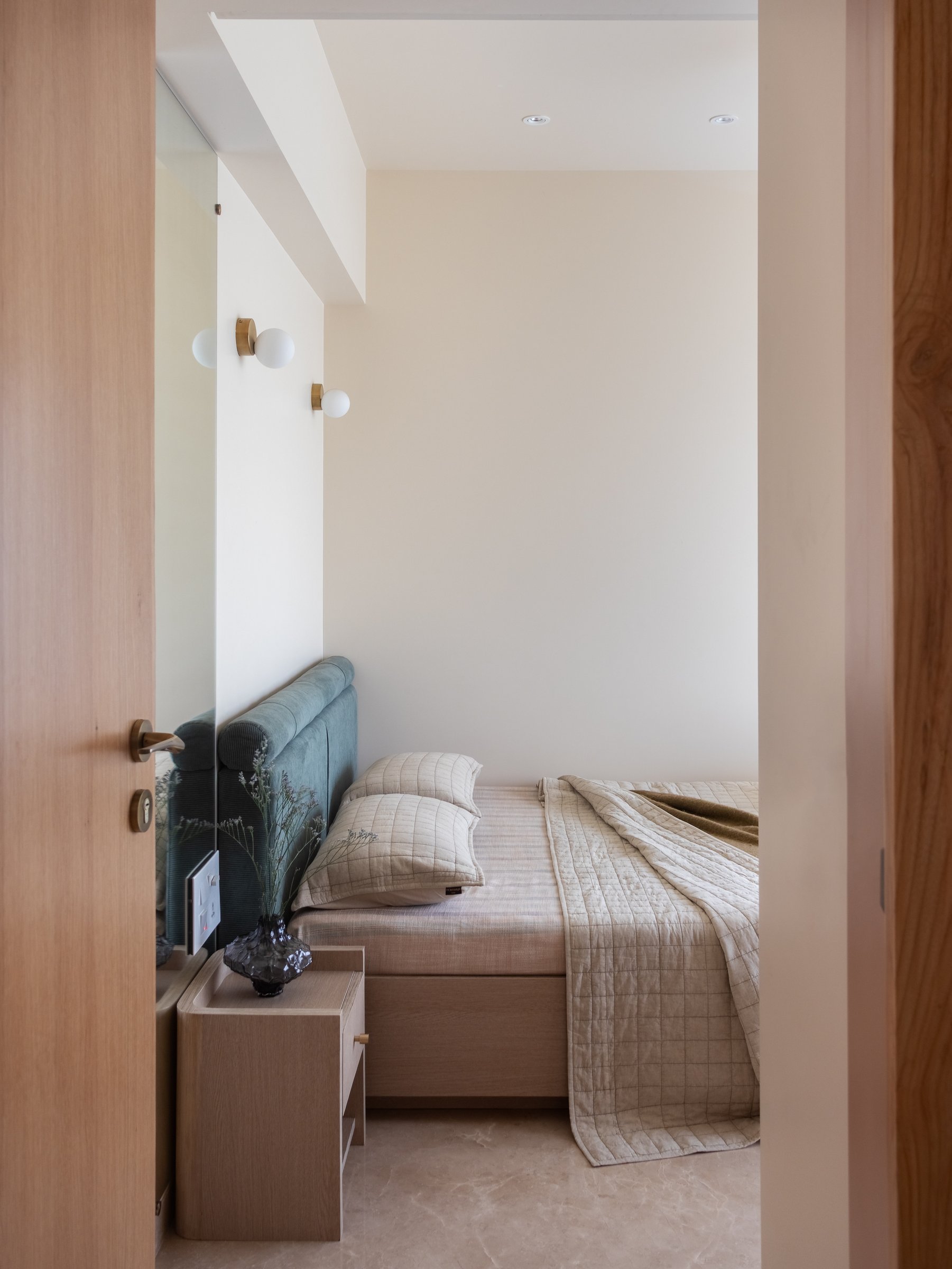 The guest bedroom, where a deep ocean-blue headboard is allowed to perform as the apartment's one departure from neutrality