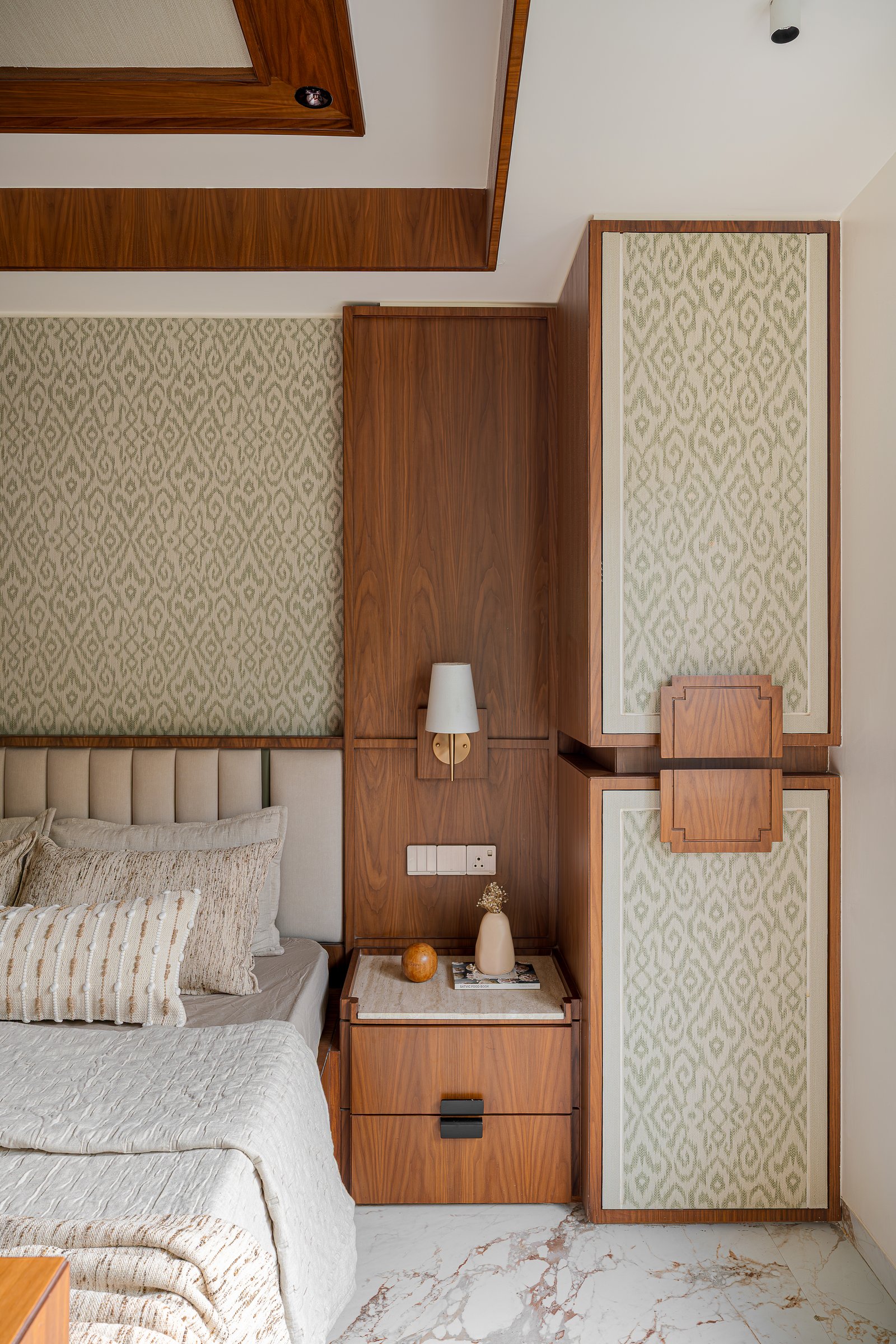 A wardrobe inset with framed panels of the same ikat that anchors the room turns storage into ornament
