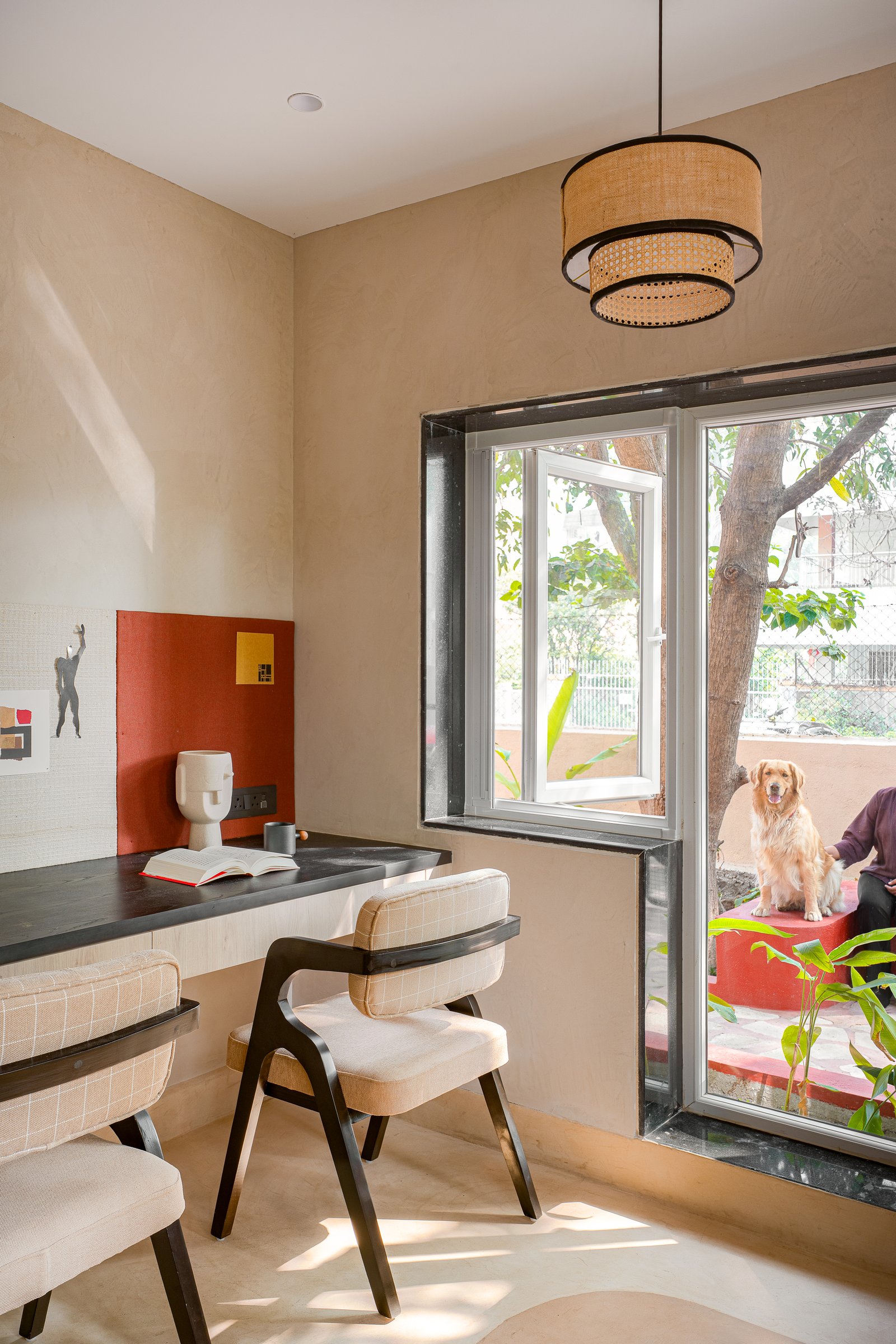 Where the desk turns the corner, a small clay-red panel anchors the studio's pinboard wall