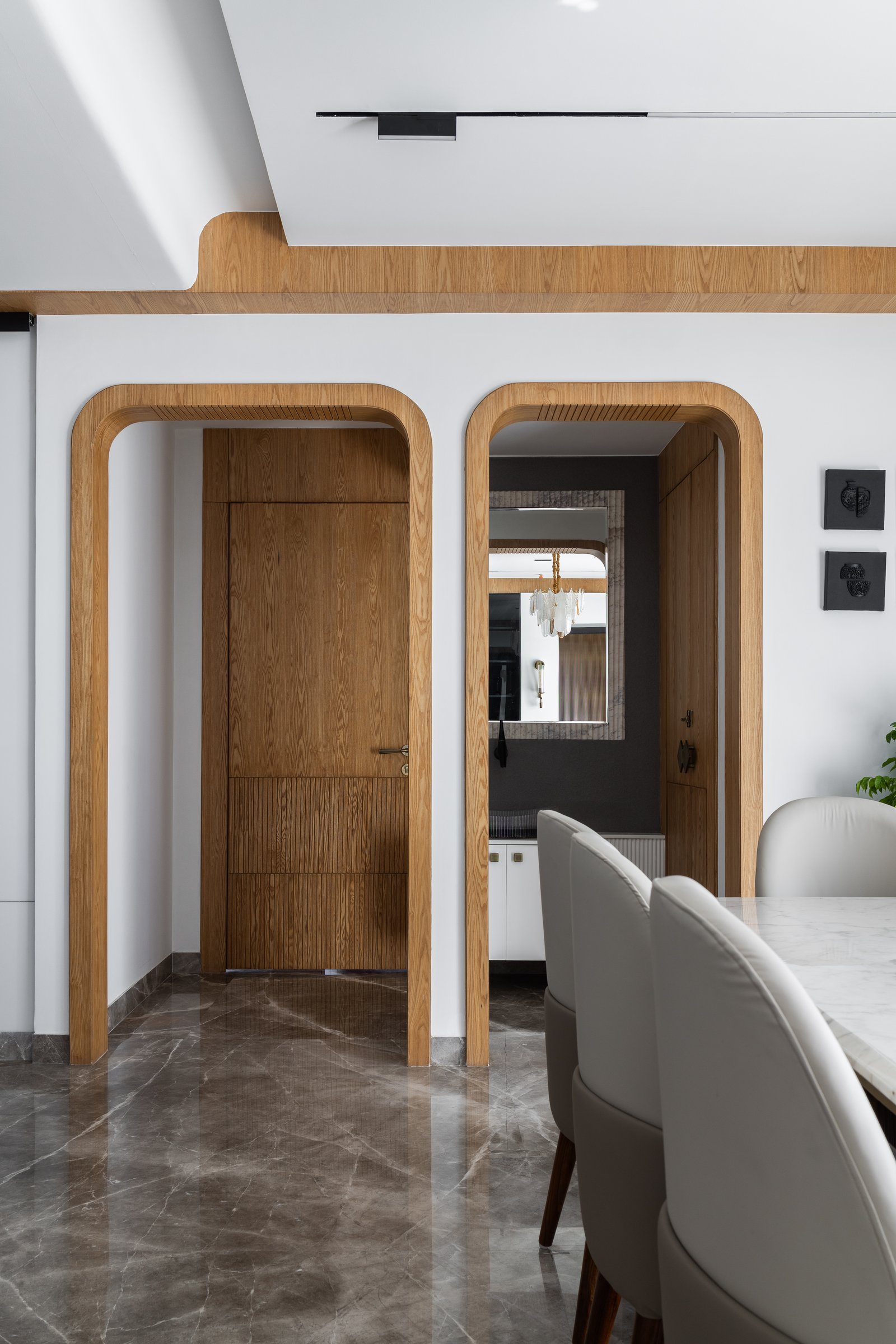 Twin arched portals in warm wood mark the threshold between dining and the private quarters