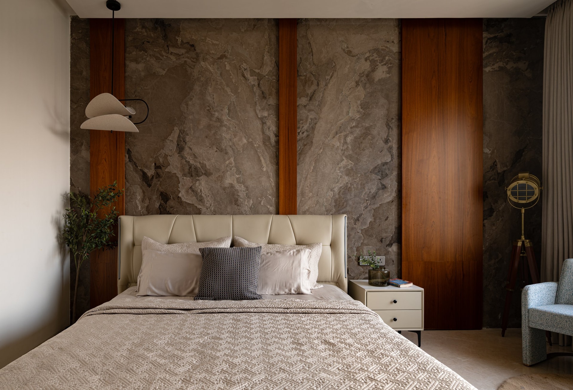 The master suite headboard wall: grey-veined stone divided by vertical teak inserts
