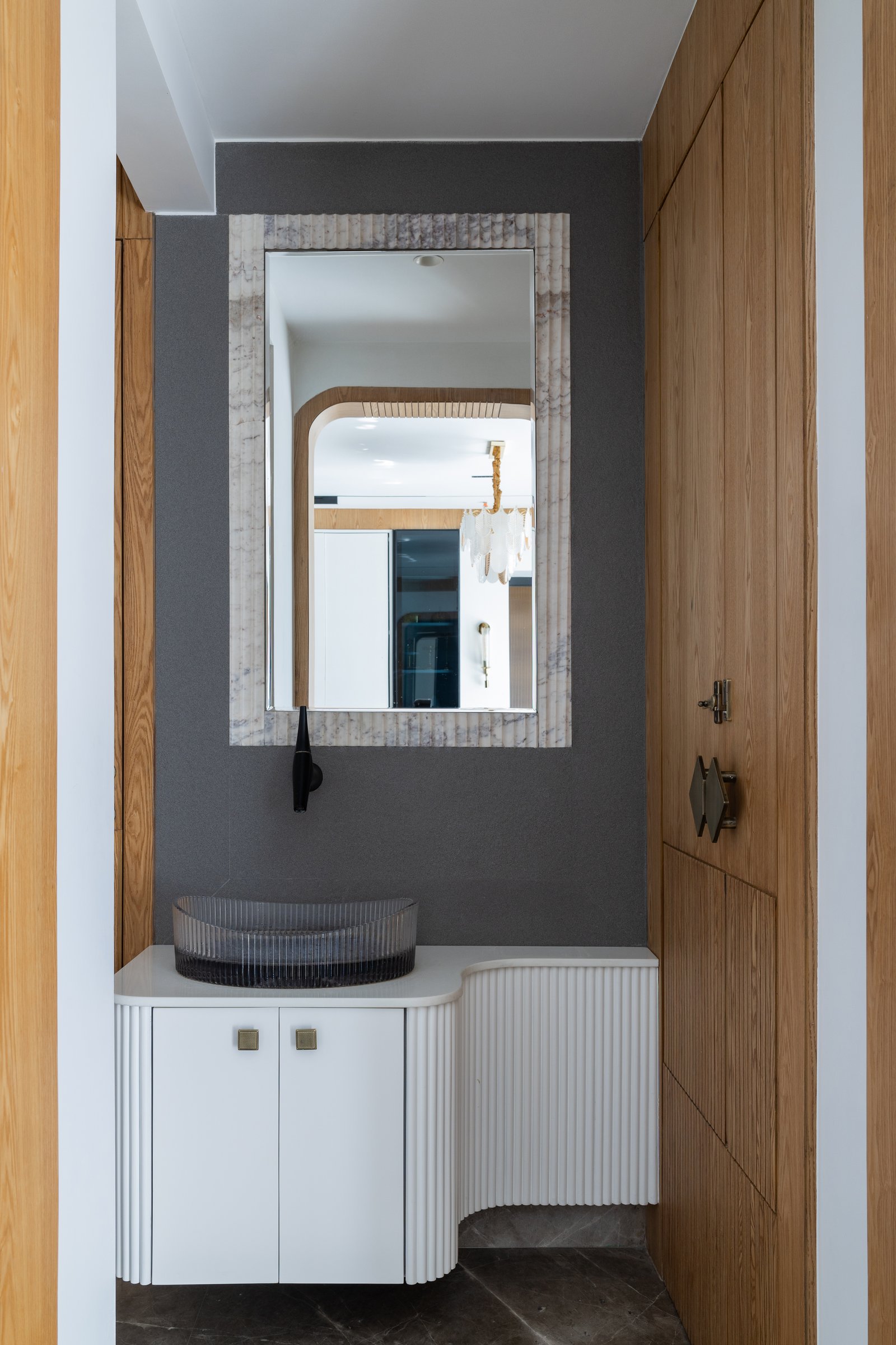 The powder area, where fluting is distilled into a sculpted curved vanity against a charcoal wall