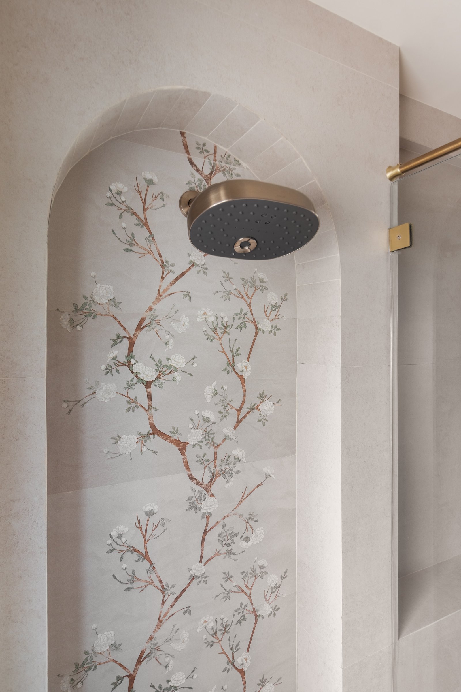 The master shower, where a hand painted floral mural inside an arched niche becomes the apartment's most private decorative gesture