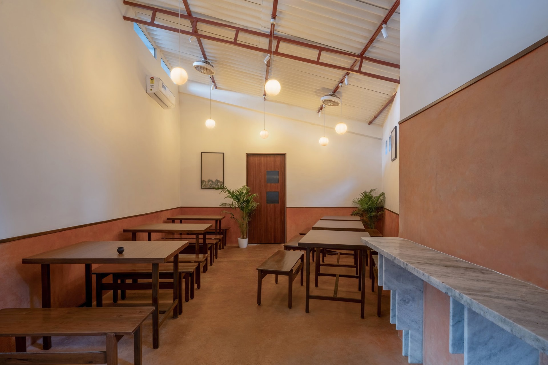 The dining hall, where IPS walls in terracotta and a pale upper register frame canteen-style seating
