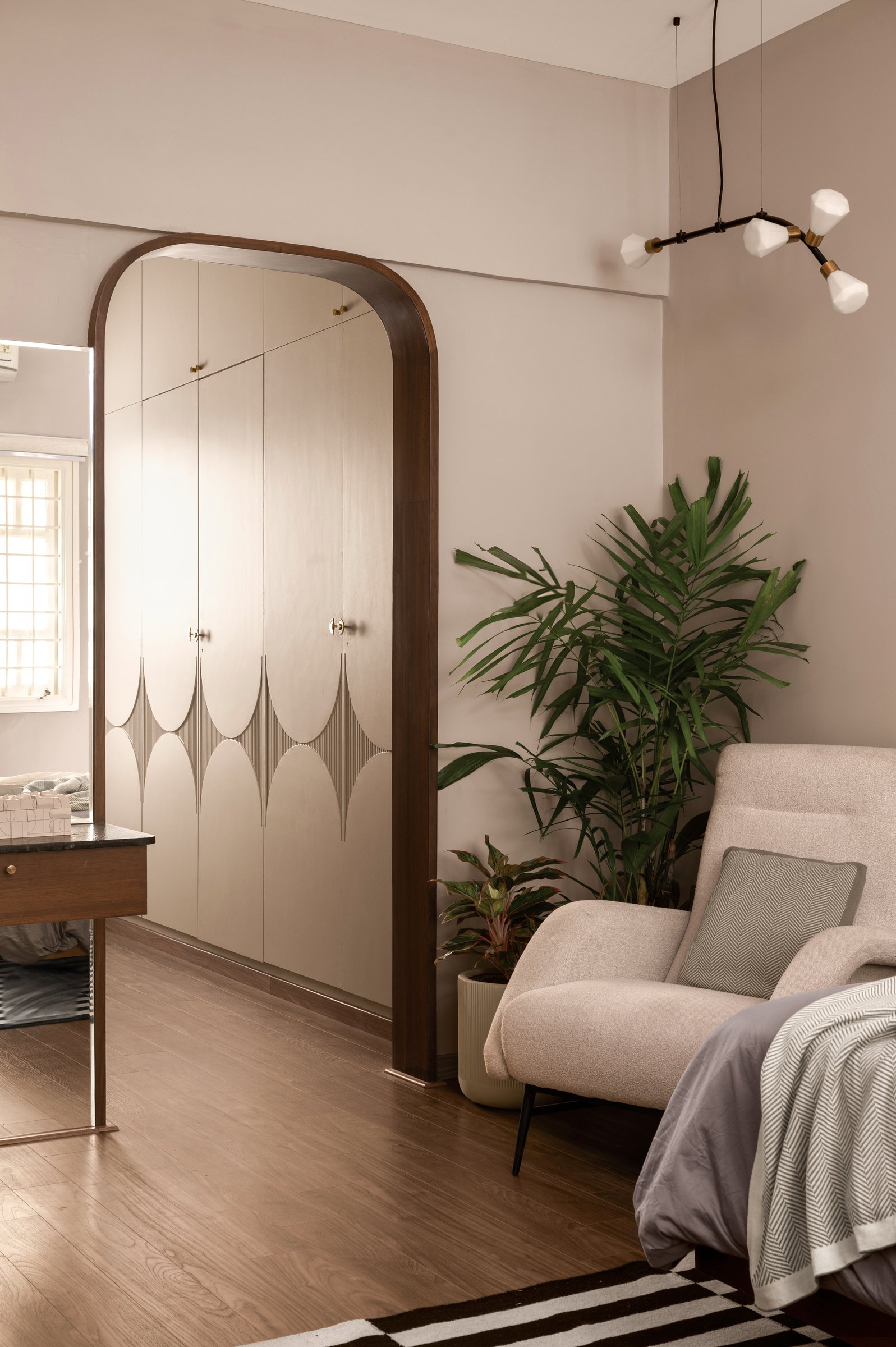 The upper-floor bedroom, where a walnut-framed arch leads to a cream wardrobe with subtle arced inlay