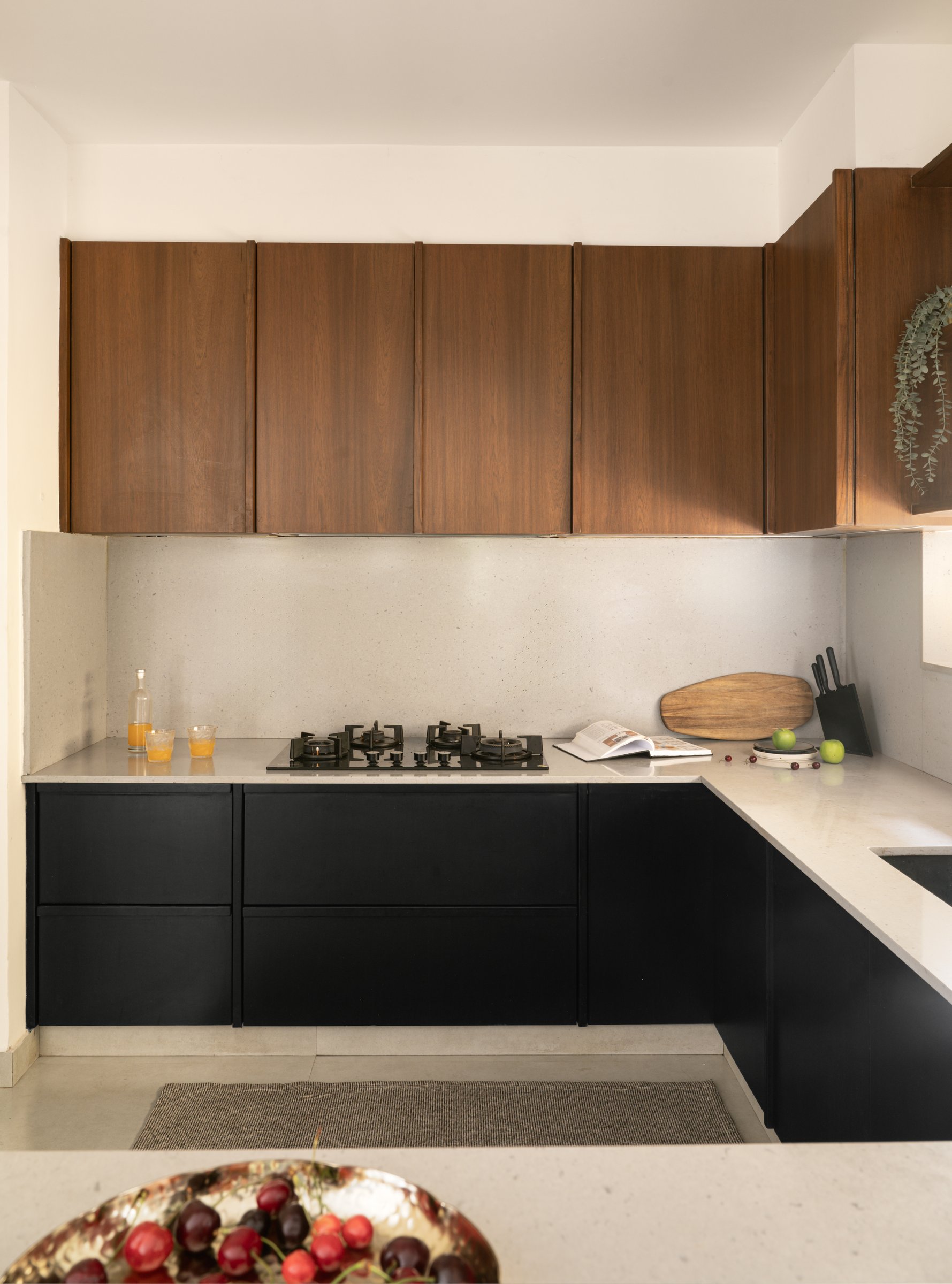 The petite kitchen, where matte black base units sit beneath a pale quartz counter and warm oak uppers run in continuous grain