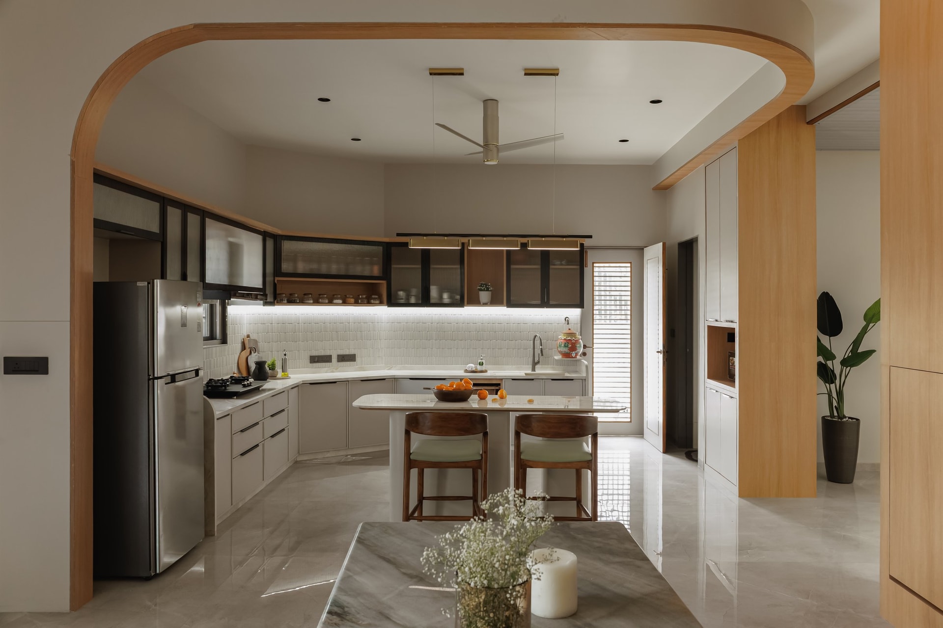The kitchen framed by a softly radiused arch, with a small marble island doubling as breakfast counter