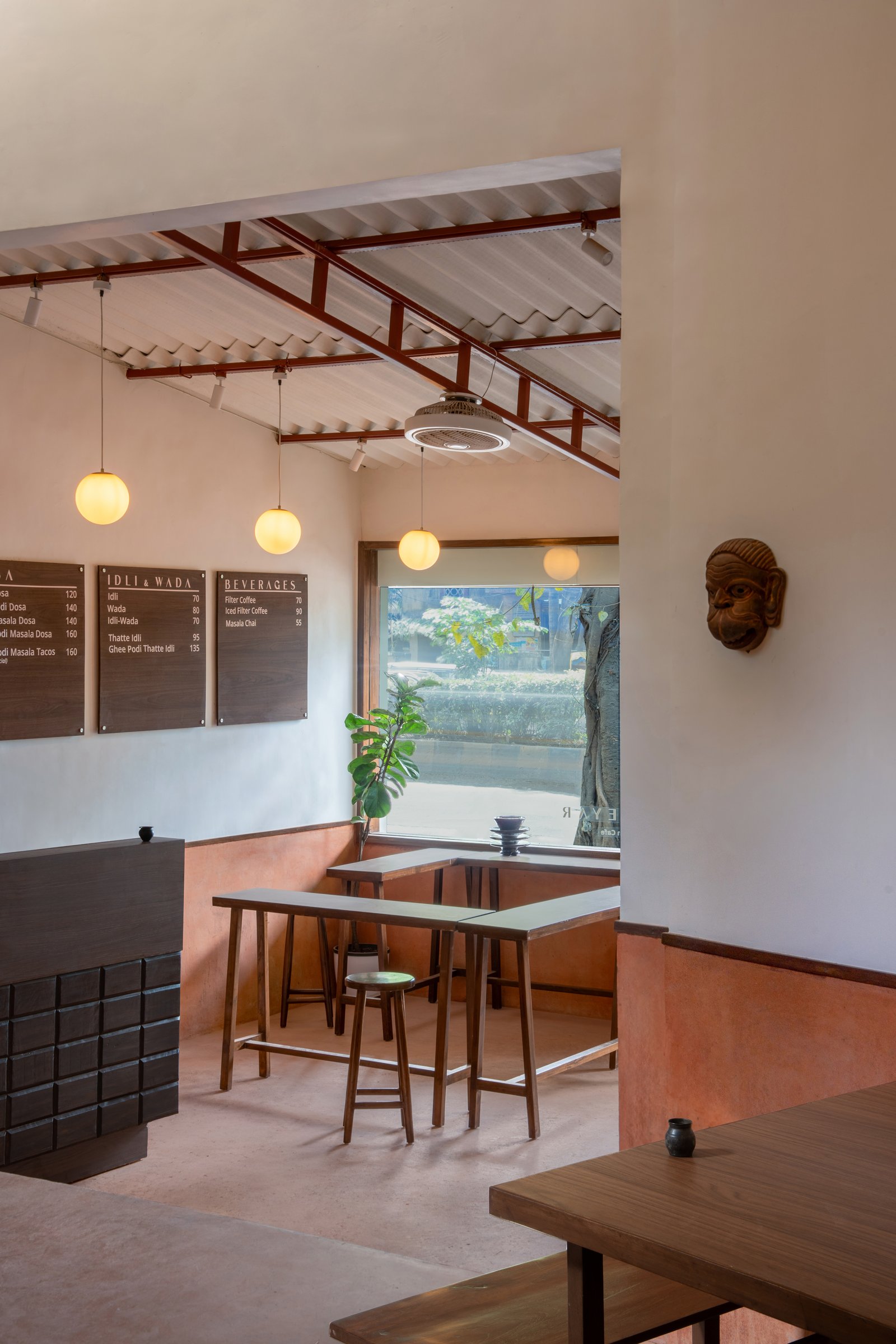 The entrance volume, where clerestory windows and a row of globe pendants establish the café's domestic rhythm