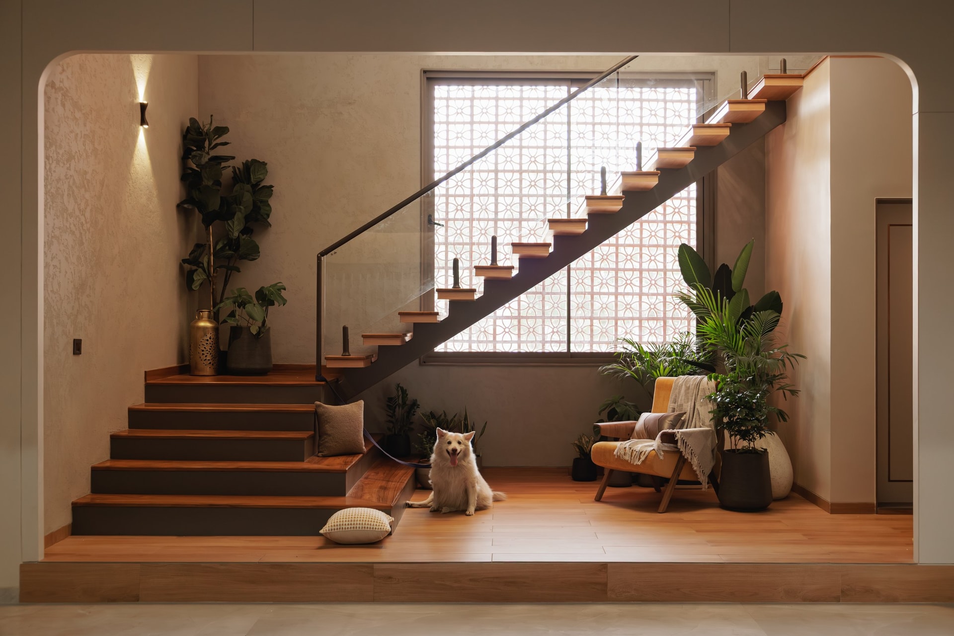 The staircase: a cantilevered timber flight rising against a brick jaali that filters the afternoon light