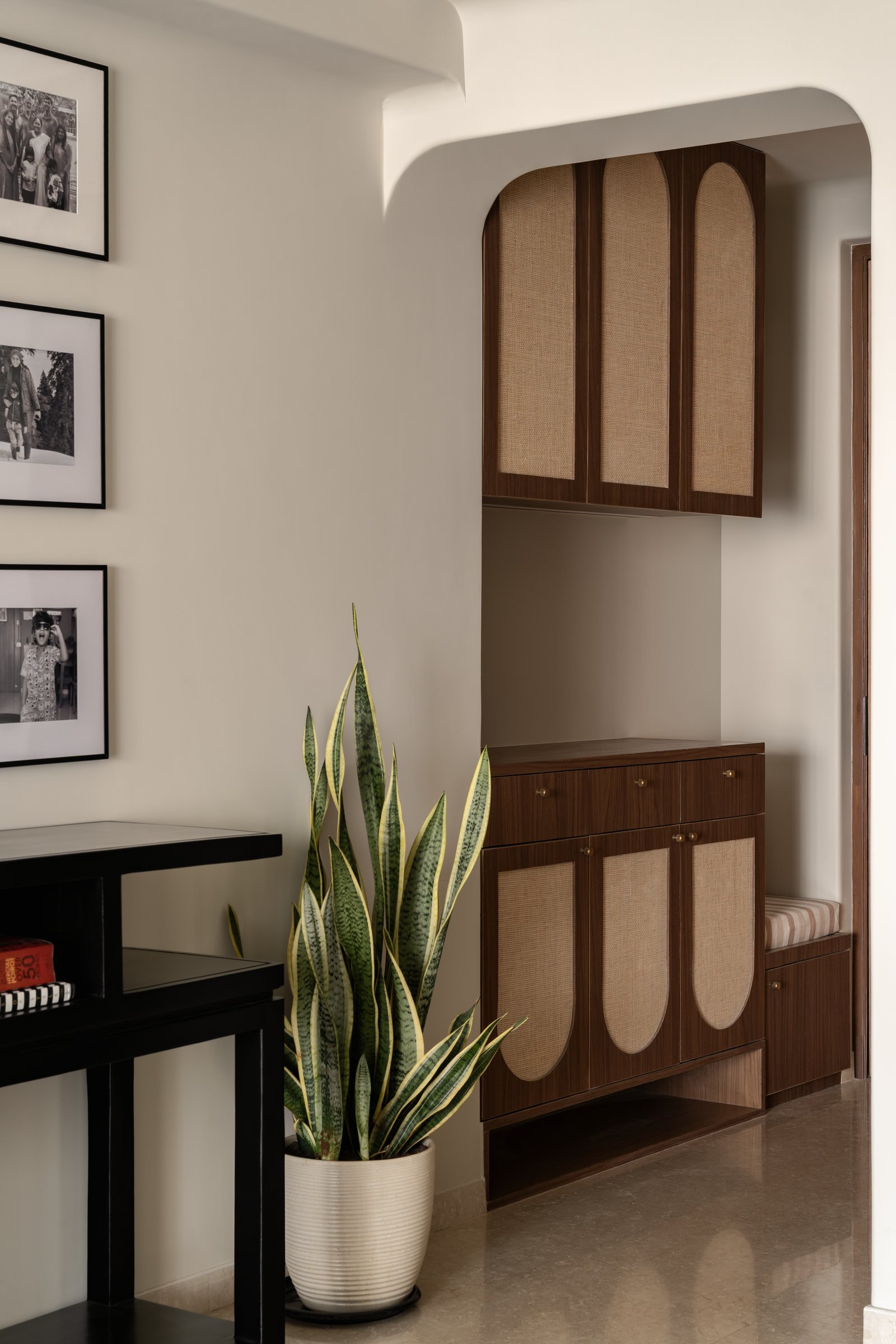 The entry niche: cane-fronted walnut joinery framed within a softly arched plaster reveal sets the home's grammar of craft and restraint