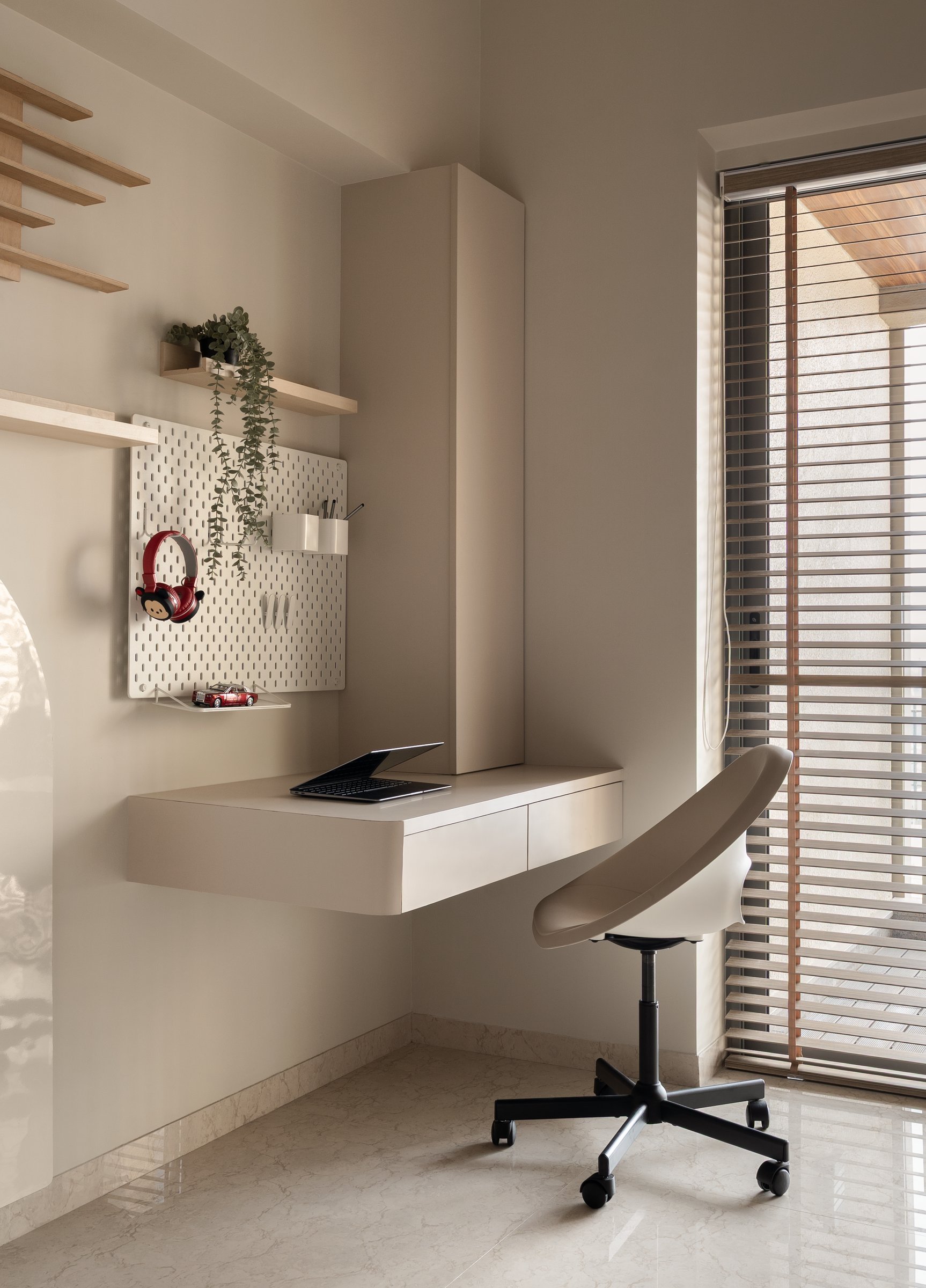 The study corner within the same room: a floating desk and slatted blinds offering economy and quiet for a child who will grow into it