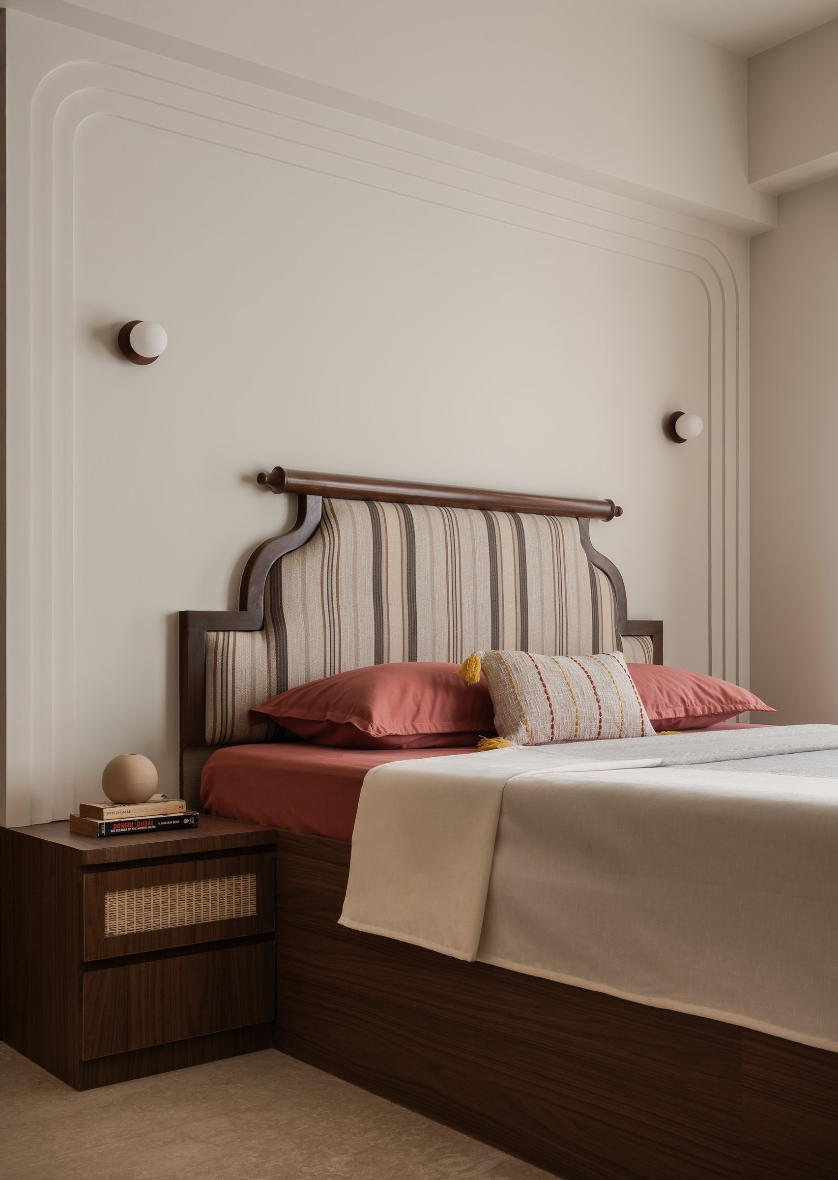 The master bedroom: a traditionally inflected headboard sits against pale plaster mouldings that echo the arches found elsewhere in the home