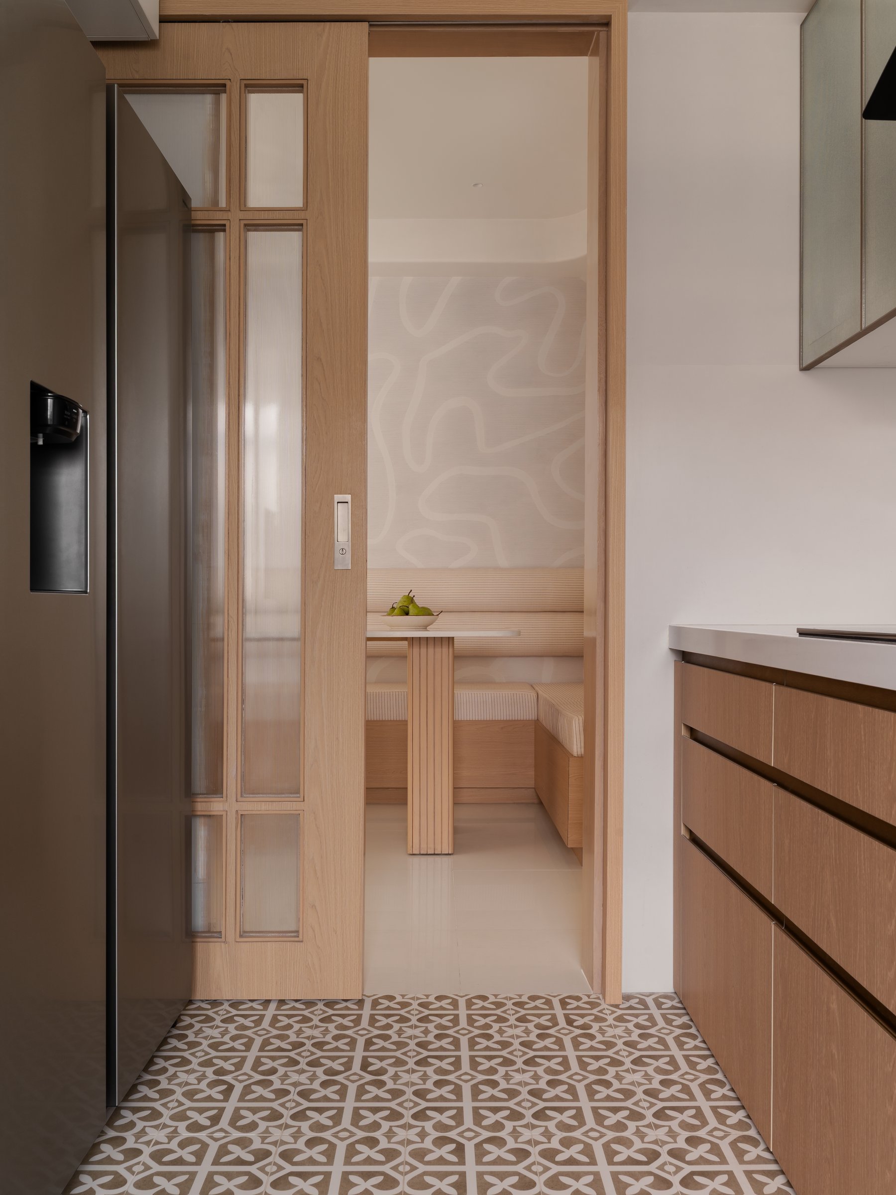 The threshold between kitchen and dining, where a reeded-glass sliding door does double duty as screen and dissolve