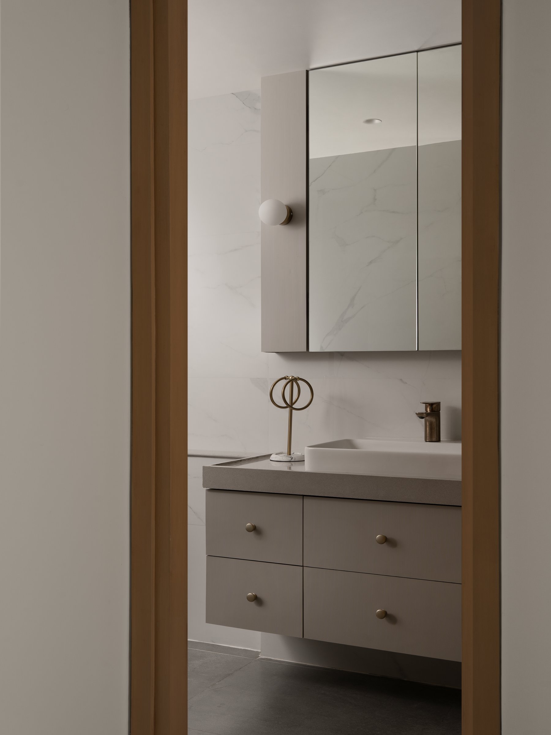 The bathroom, where ribbed vanity fronts and veined stone cladding thread a single textural idea through the home's private edge