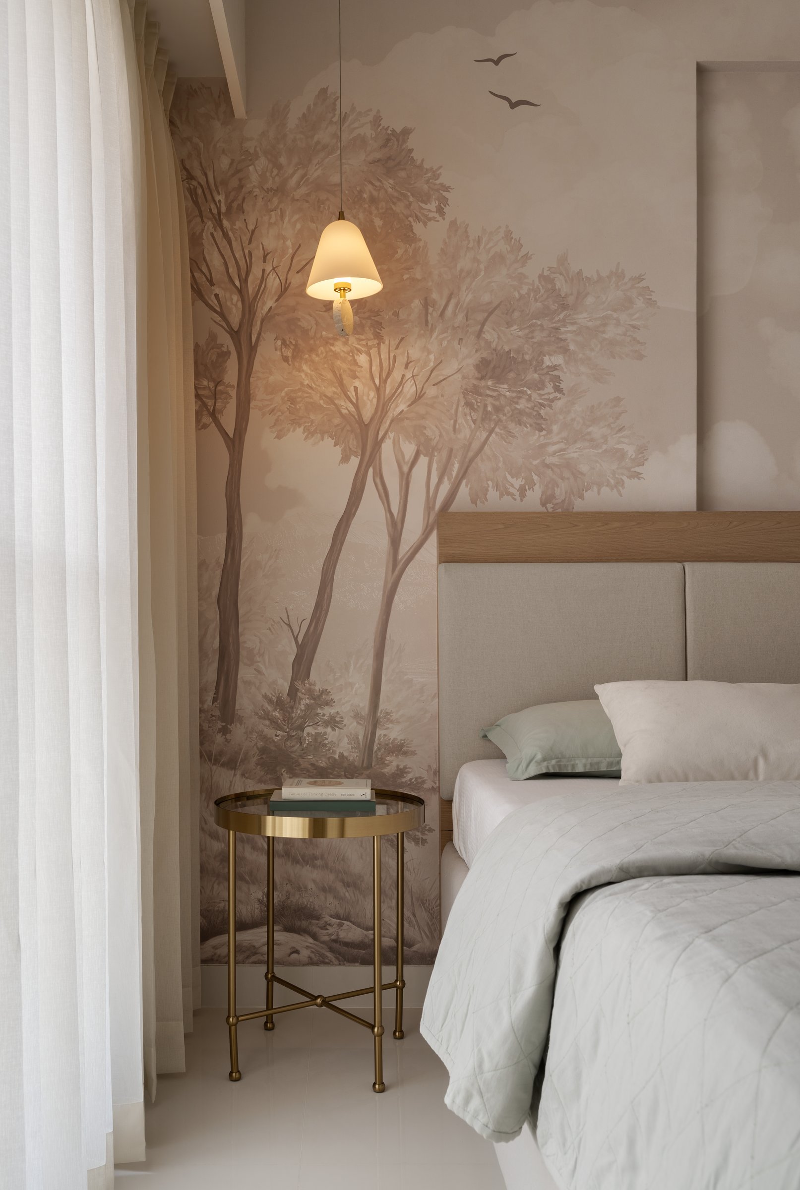 A closer view of the bedside, where a small ceramic pendant and a brass side table lend intimacy without competing with the mural