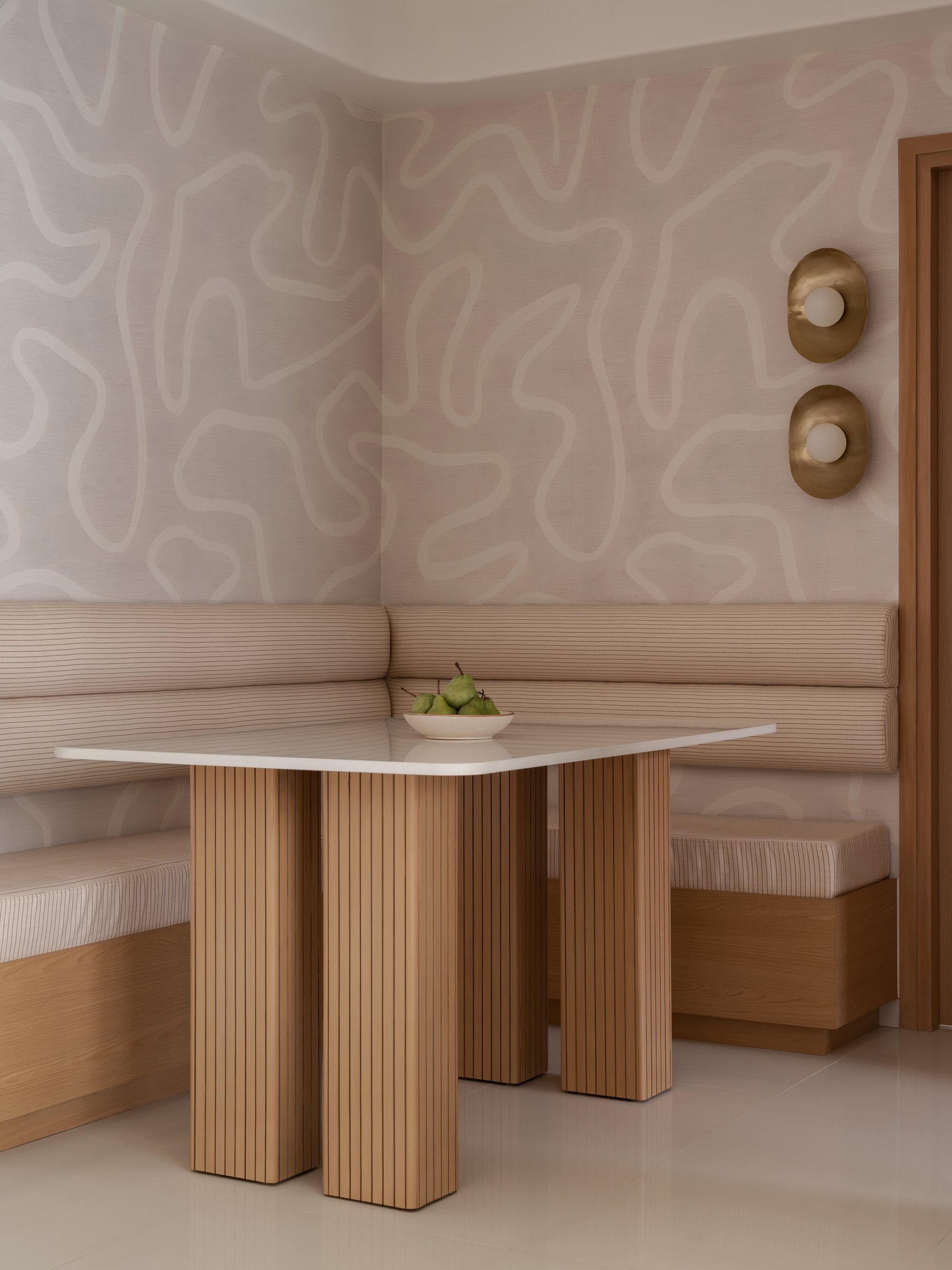 The dining nook, where a ribbed wood table and an L-shaped striped banquette make the case for built-in intimacy