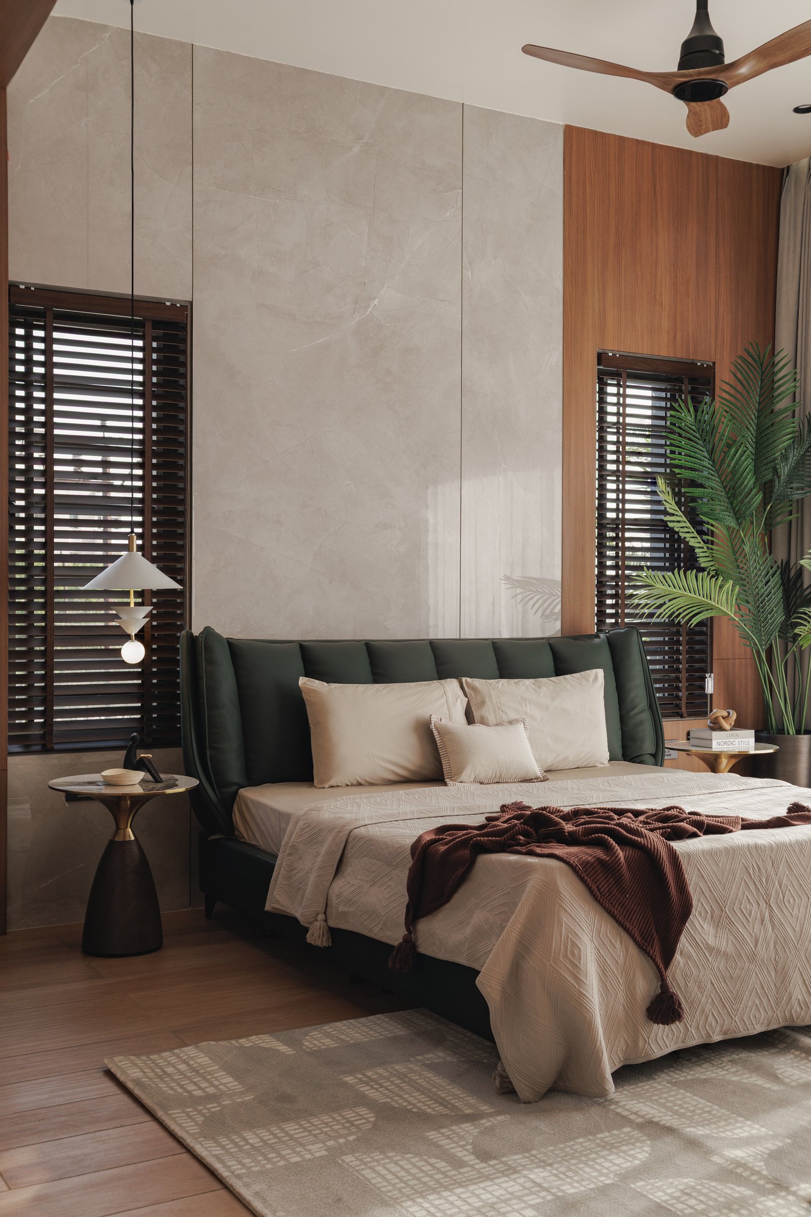 Closer to the bed, the deep green upholstered headboard anchors the composition against the pale stone wall