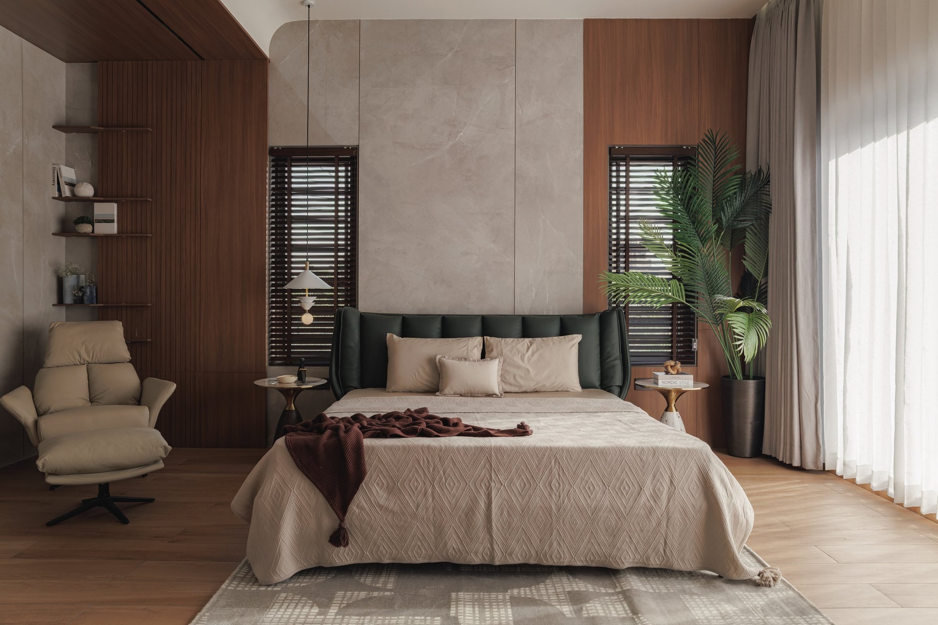 The master bedroom settles into a deeper palette of stone, dark wood, and a wing-shouldered green headboard