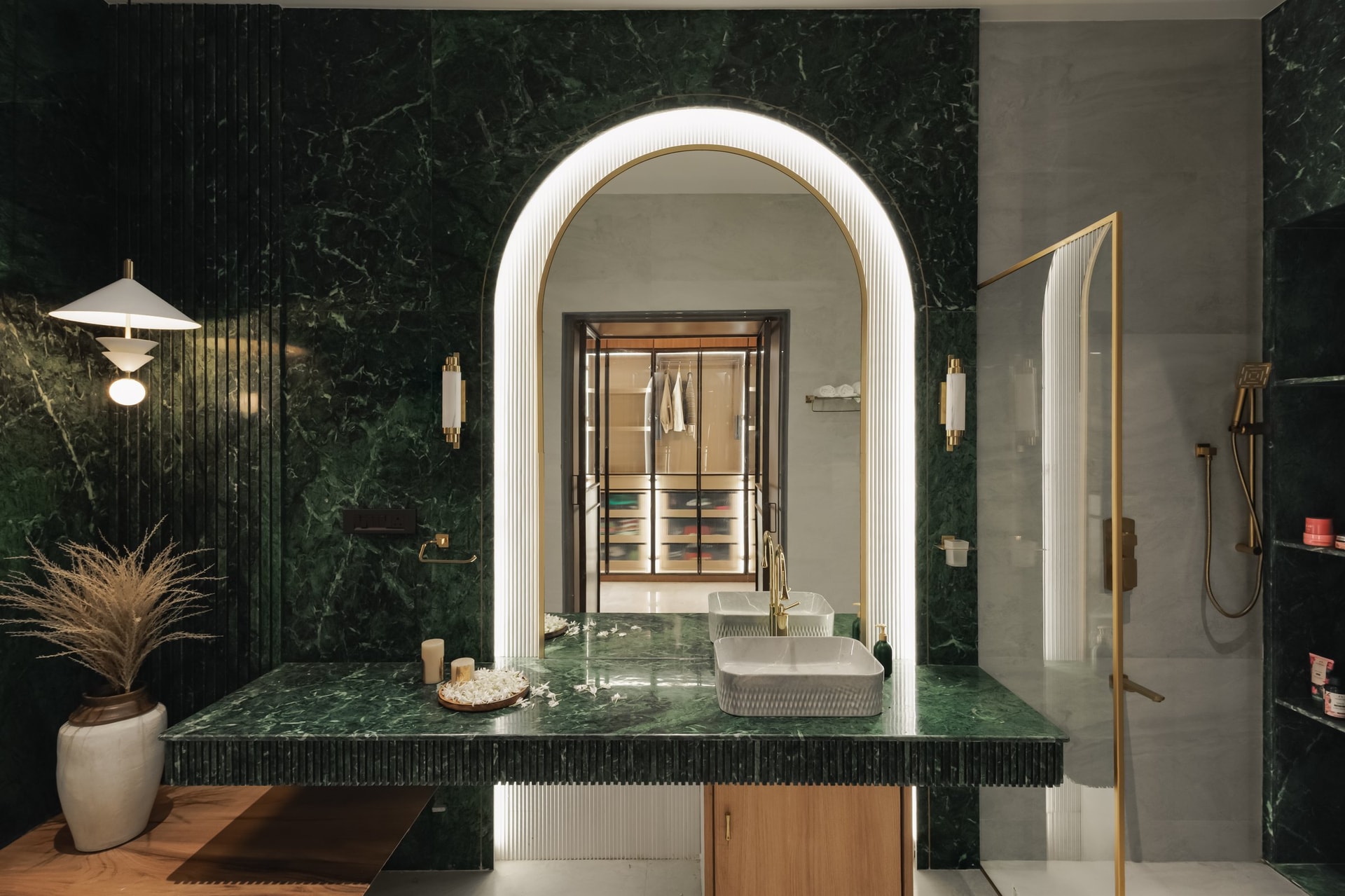 The master bathroom: deep green Baroda stone cloaks the vanity wall and frames a backlit arched mirror