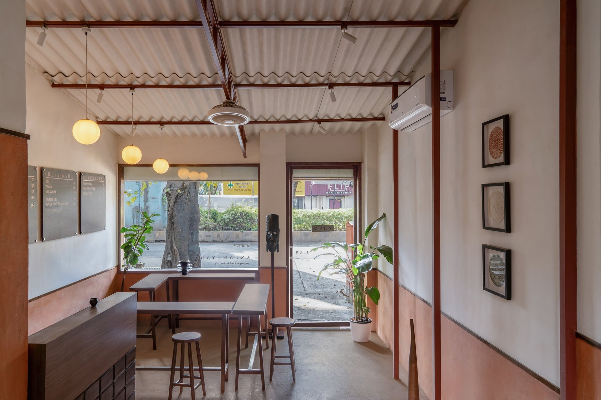 The threshold view, where signage, mask, and street tree negotiate the boundary between café and street