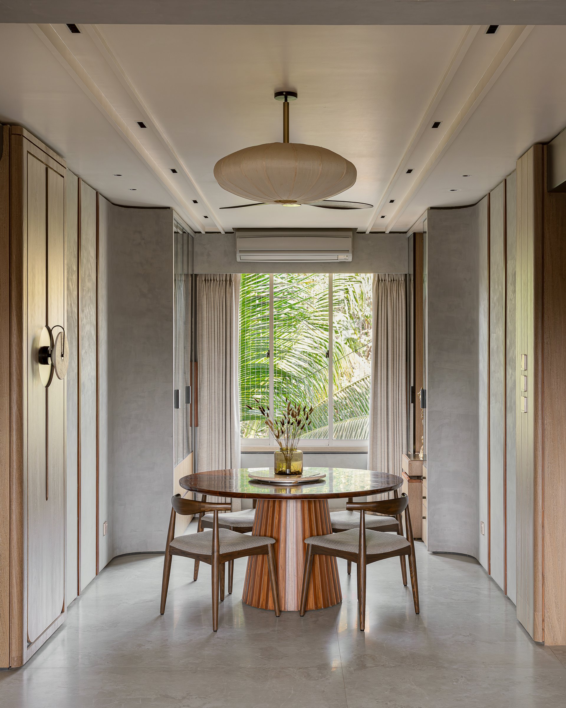 The dining room, framed by full-height plastered cabinetry that holds everything the household needs without asking to be noticed