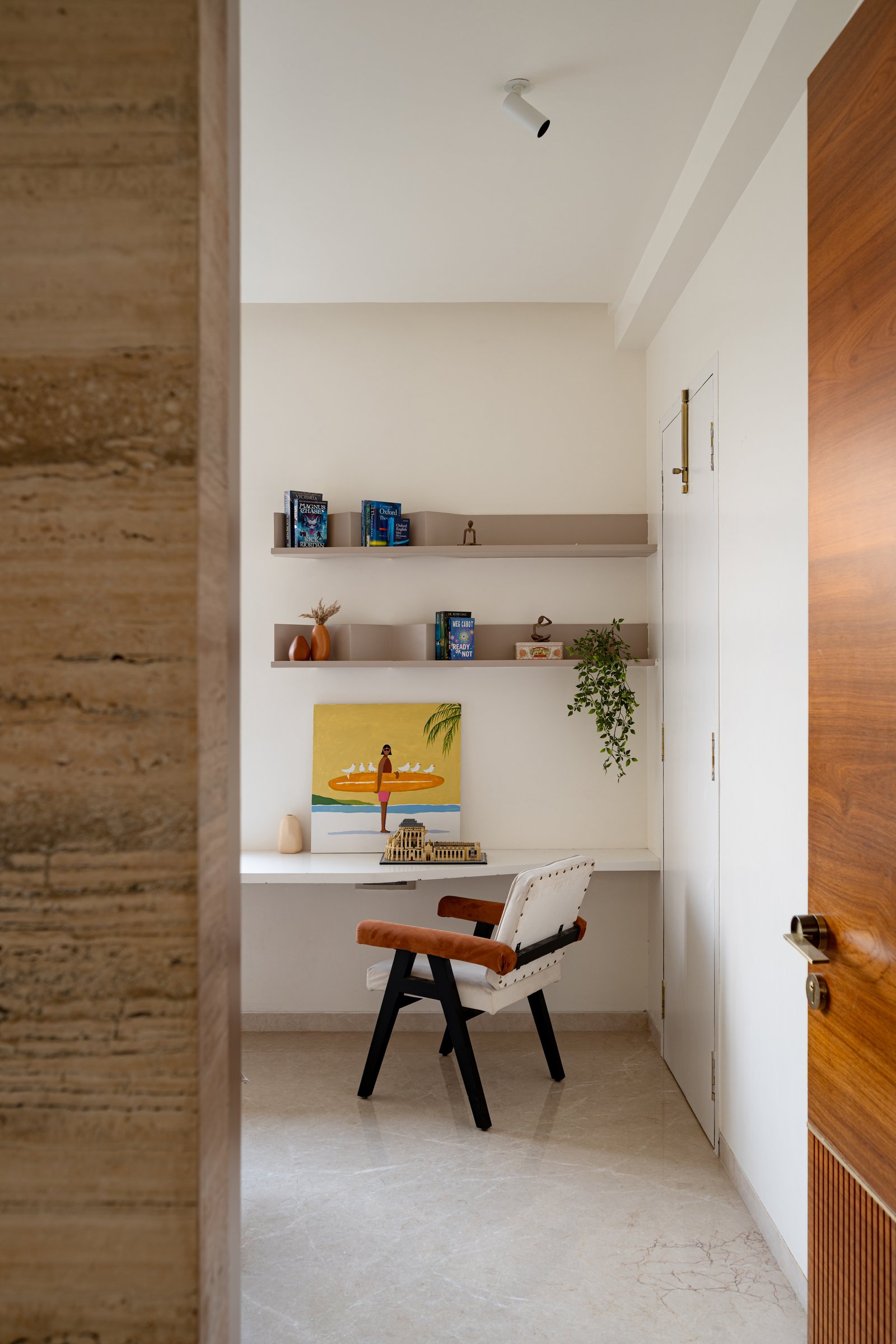 A small study tucked between a travertine wall and a teak door, kept deliberately spare