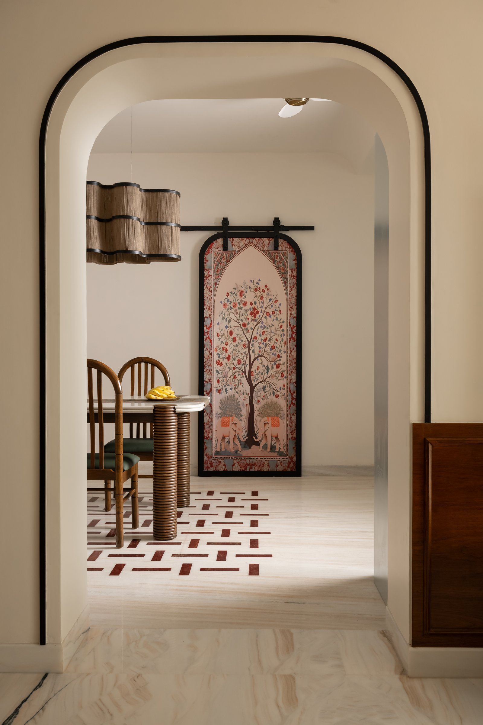 The arched corridor between dining and the adjoining zone, anchored by a pichwai-inspired tree-of-life artwork