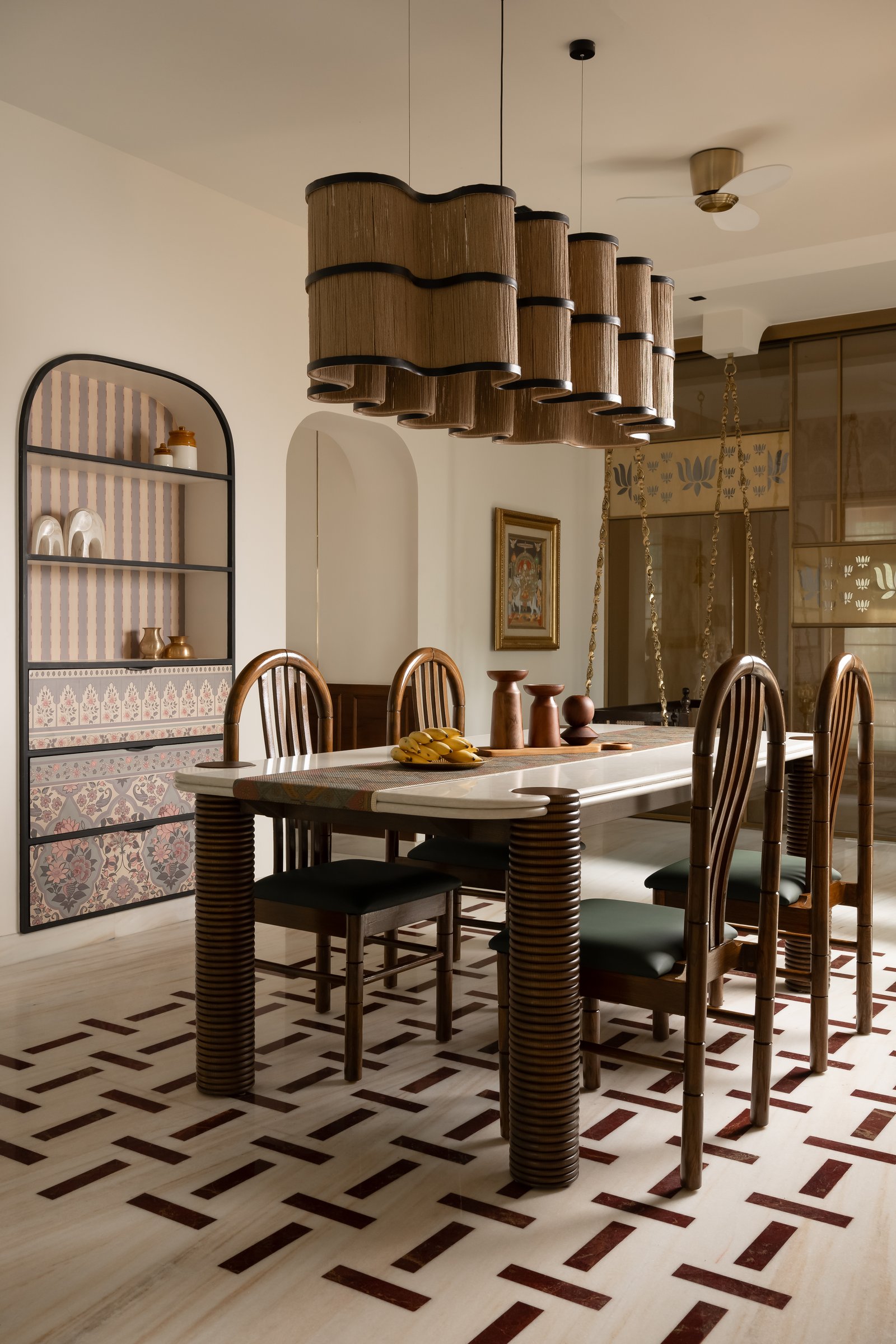The dining area, where ribbed wooden columns support a stone-topped table beneath rope-wrapped pendants