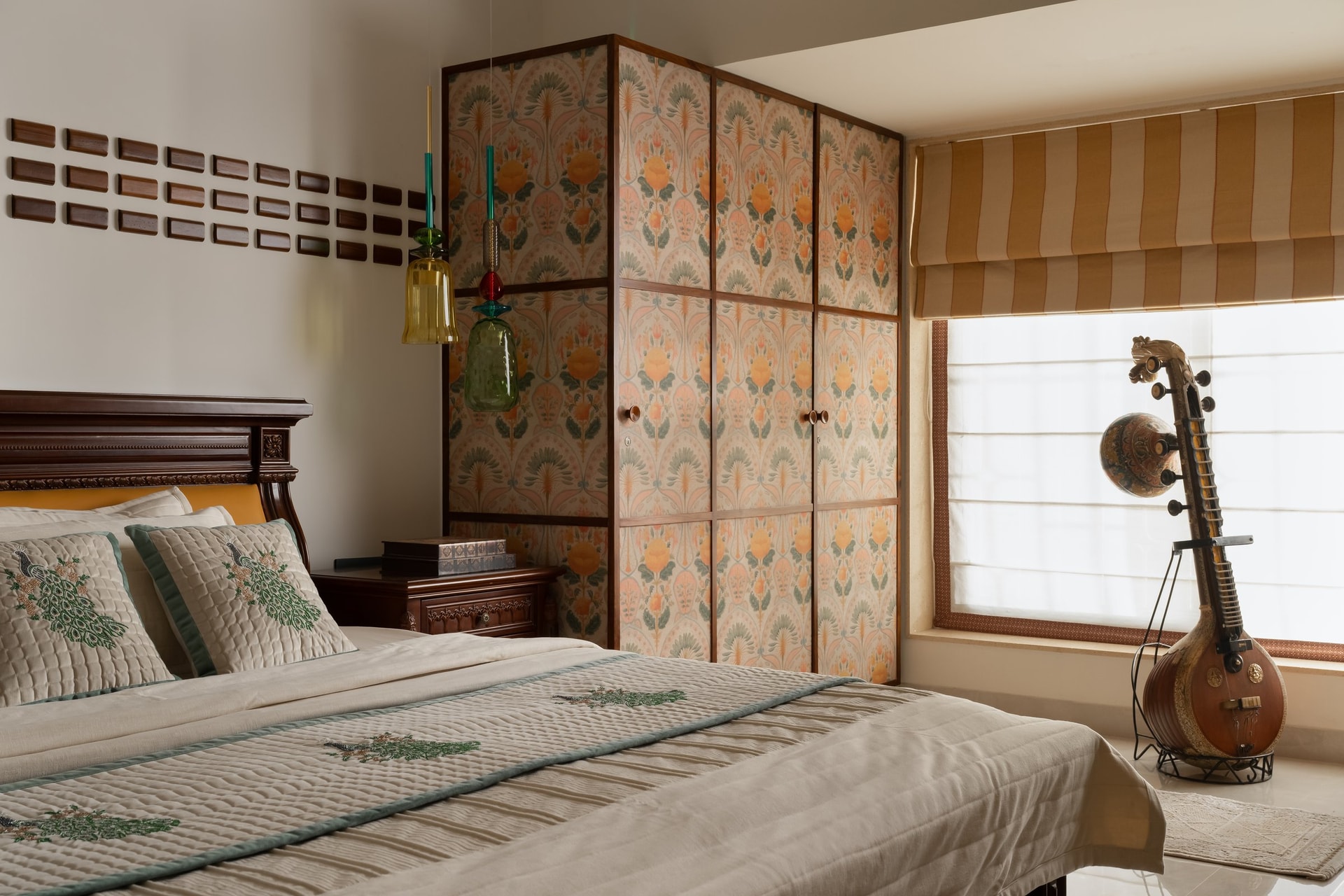 The second bedroom, where art-nouveau-inflected wallpapered wardrobes meet a cluster of coloured glass pendants