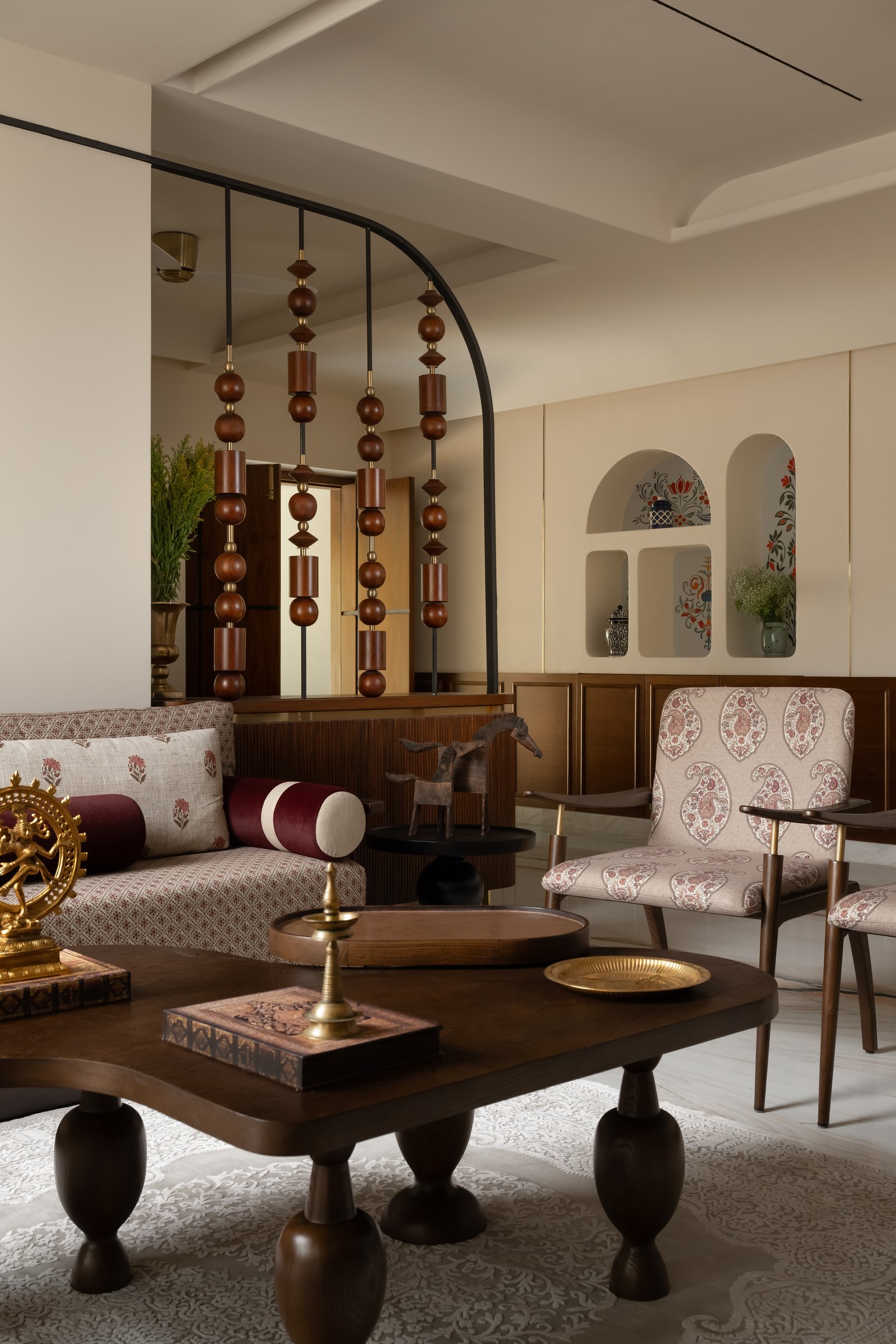 The principal living room, where a block-printed sofa, paisley armchairs and a beaded screen establish the home's material conversation