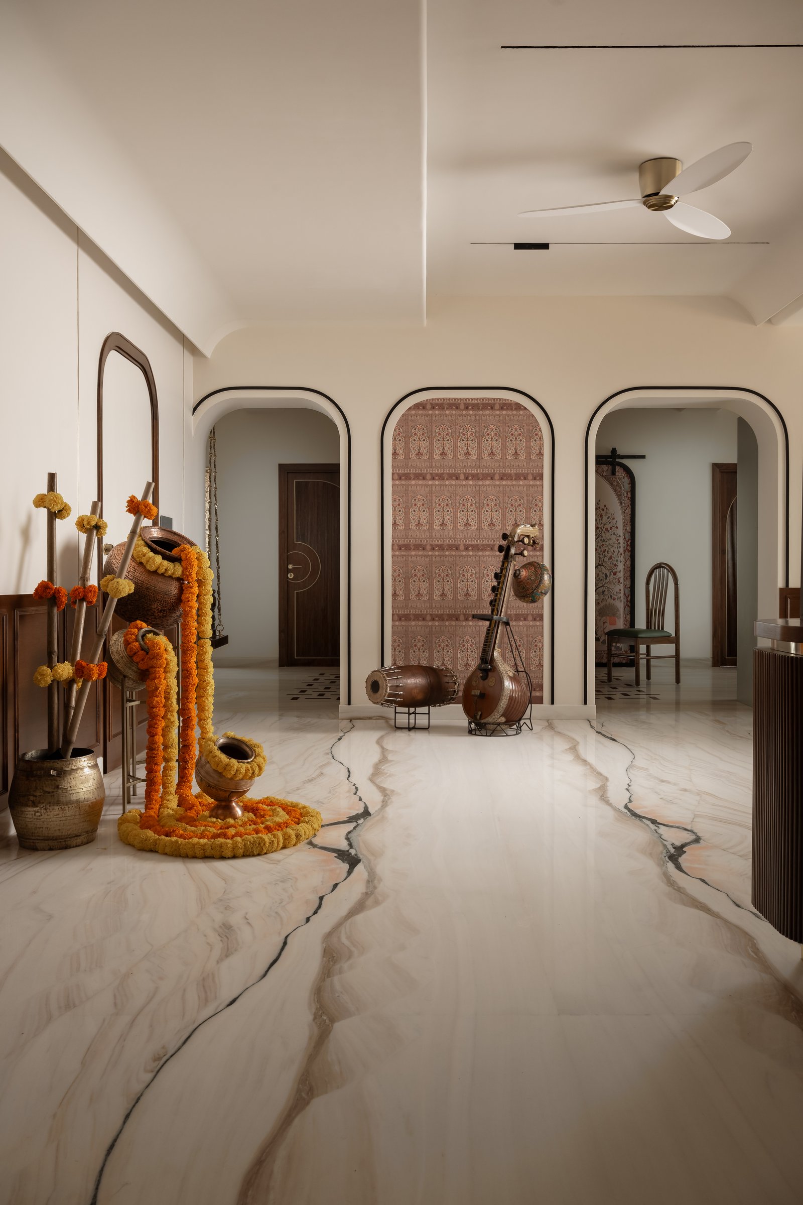 The foyer, where a river of veined marble and three arched openings frame the home's ancestral brass and stringed instruments