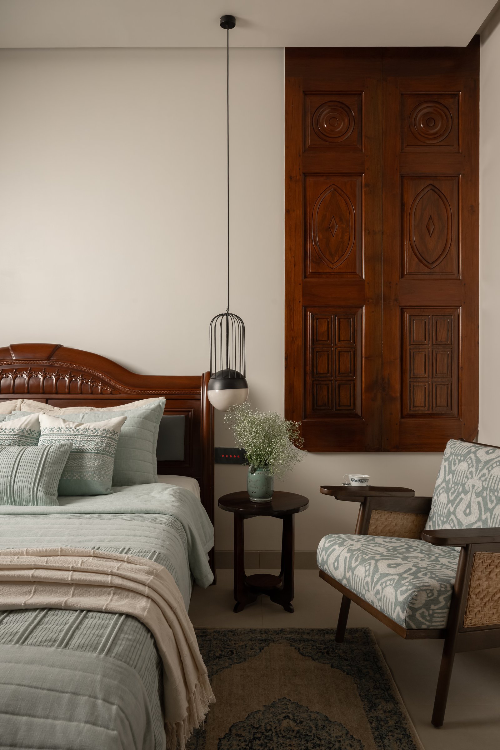 The master bedroom, where a section of the original temple door is mounted as artwork beside a carved wooden bed