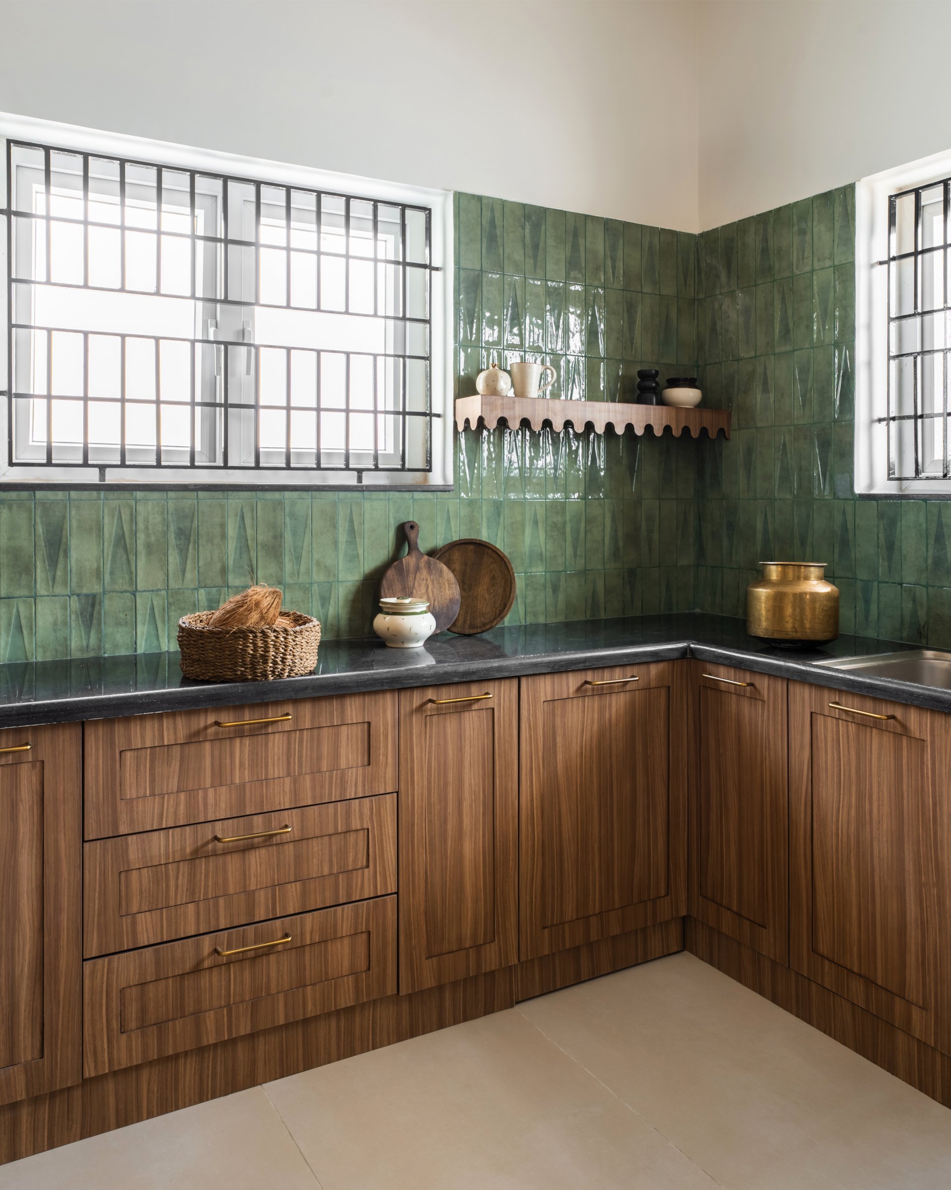 The kitchen's two-material grammar: hand-laid green tile above, wood-grained cabinetry below