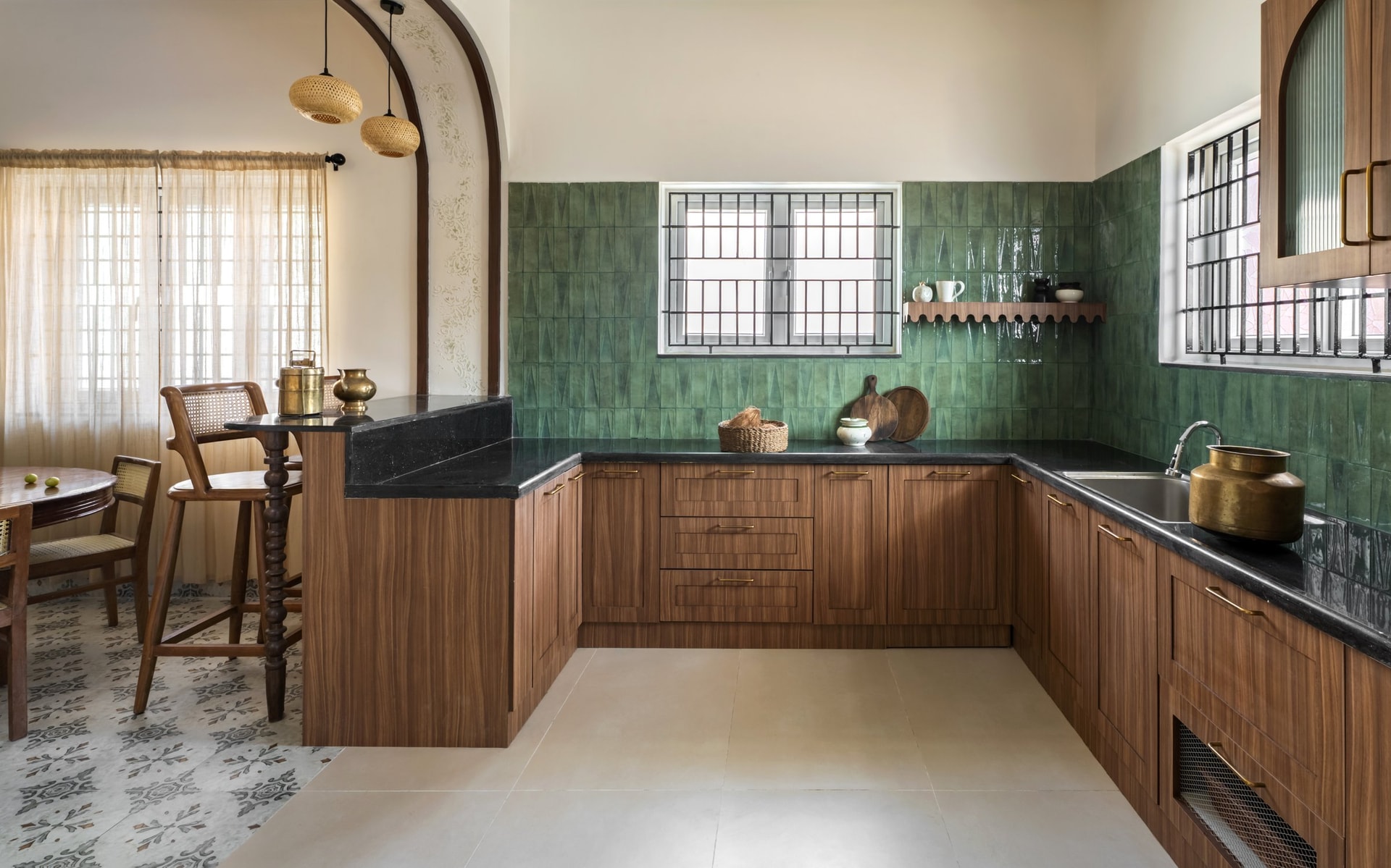 The kitchen, with walnut-toned cabinetry under a dark stone counter and a glazed green-tile backsplash